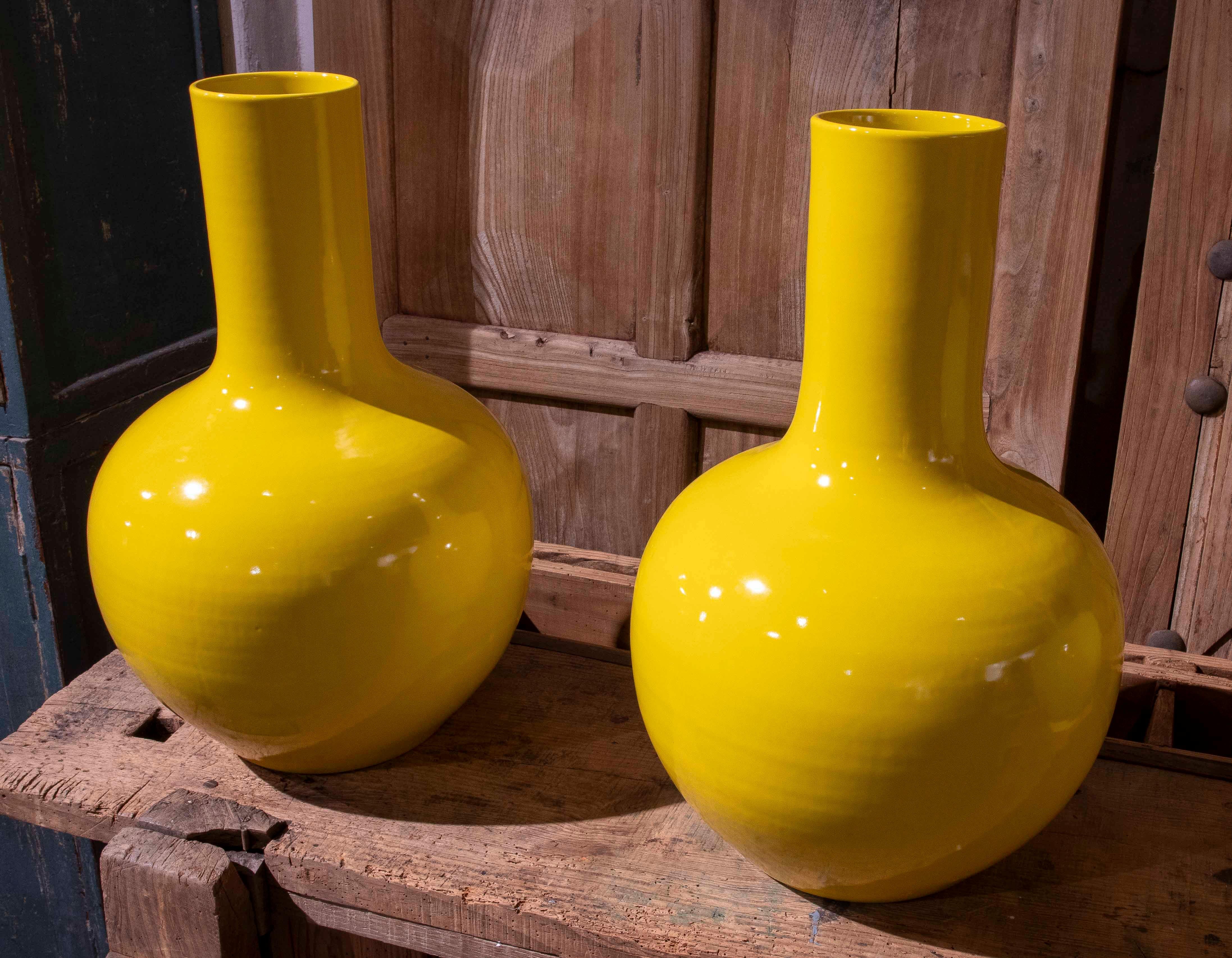 Une élégante paire de vases en céramique aux formes botaniques allongées, finis dans une glaçure jaune vibrante qui illumine n'importe quel espace. Leur silhouette sculpturale, avec une base globulaire et un cou haut et élancé, en fait des pièces