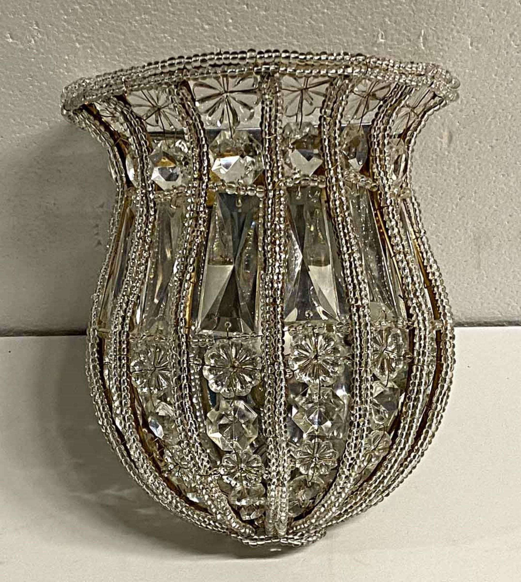 2000s Venetian clear crystal basket wall sconce with a gilt metal ribbed frame traced with decorative beading and trimmed with alternating cut crystal. Uses two 60 watt candelabra bulbs. 8.5 inches high. Small quantity available at time of posting.