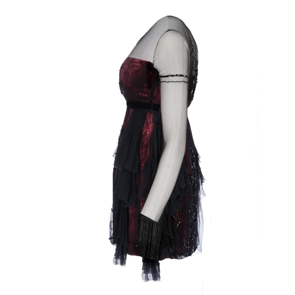 Alberta Ferretti burgundy velvet short dress covered with black tulle veil. Long sleeves, high waist, sequins and beads embroideries, beaded fringes on the cuffs and decorative flounces. Concealed side zip fastening.
Item shows a small hole along
