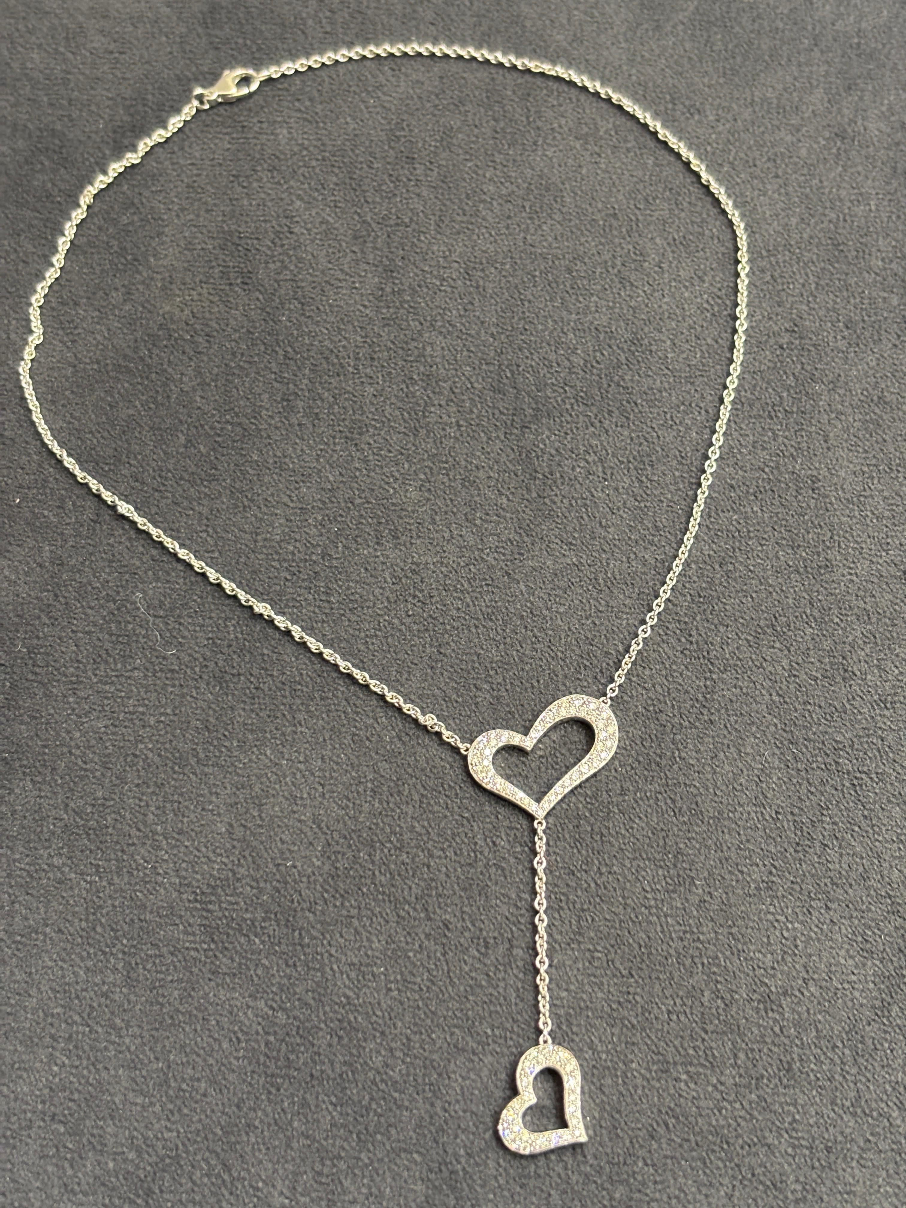 Ce charmant collier Piaget des années 1990 se compose d'un petit cœur suspendu à une chaîne fine à partir d'un plus grand cœur. En or blanc 18 carats, les deux cœurs sont recouverts de diamants de taille ronde. La longueur du collier est de 40 cm et
