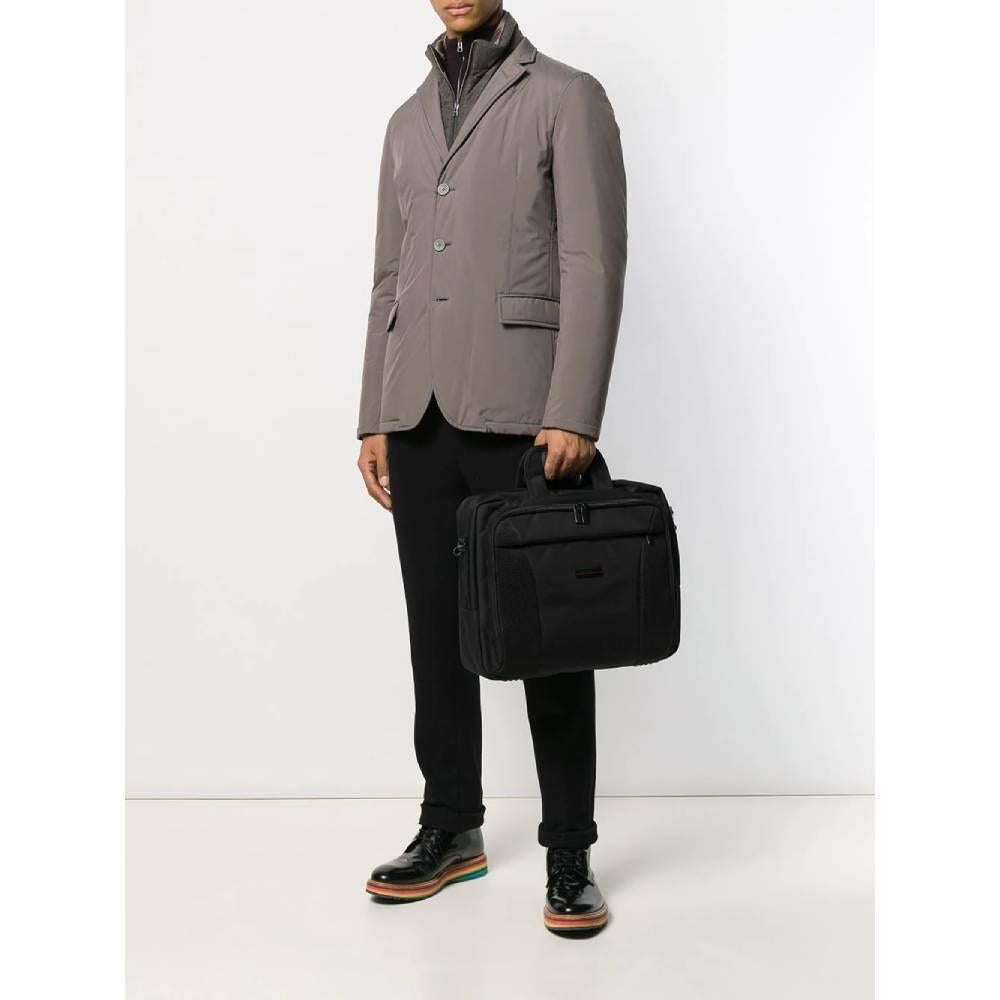Pierre Cardin briefcase in black nylon with logoed front plate. It has two external compartments with double-slider zip closure and a zip pocket, two handles and an adjustable and removable shoulder strap. Internal pockets and padded tablet or