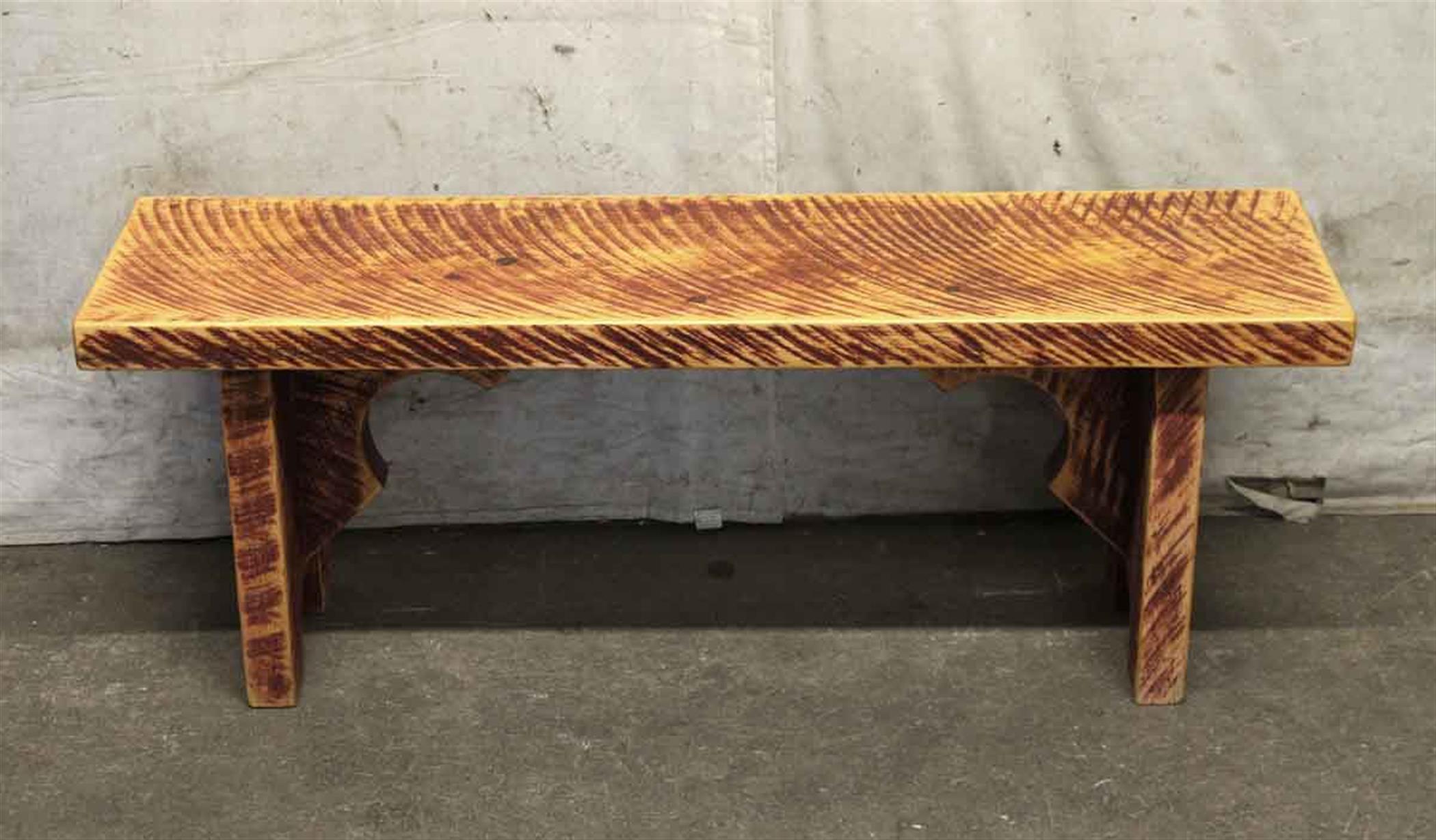 1990s pine bench with a unique stripe-like finish caused by the saw blades rotating at the saw mill. The bench is both a mixture of light and dark wood tones. This can be seen at our 302 Bowery location in Manhattan.
