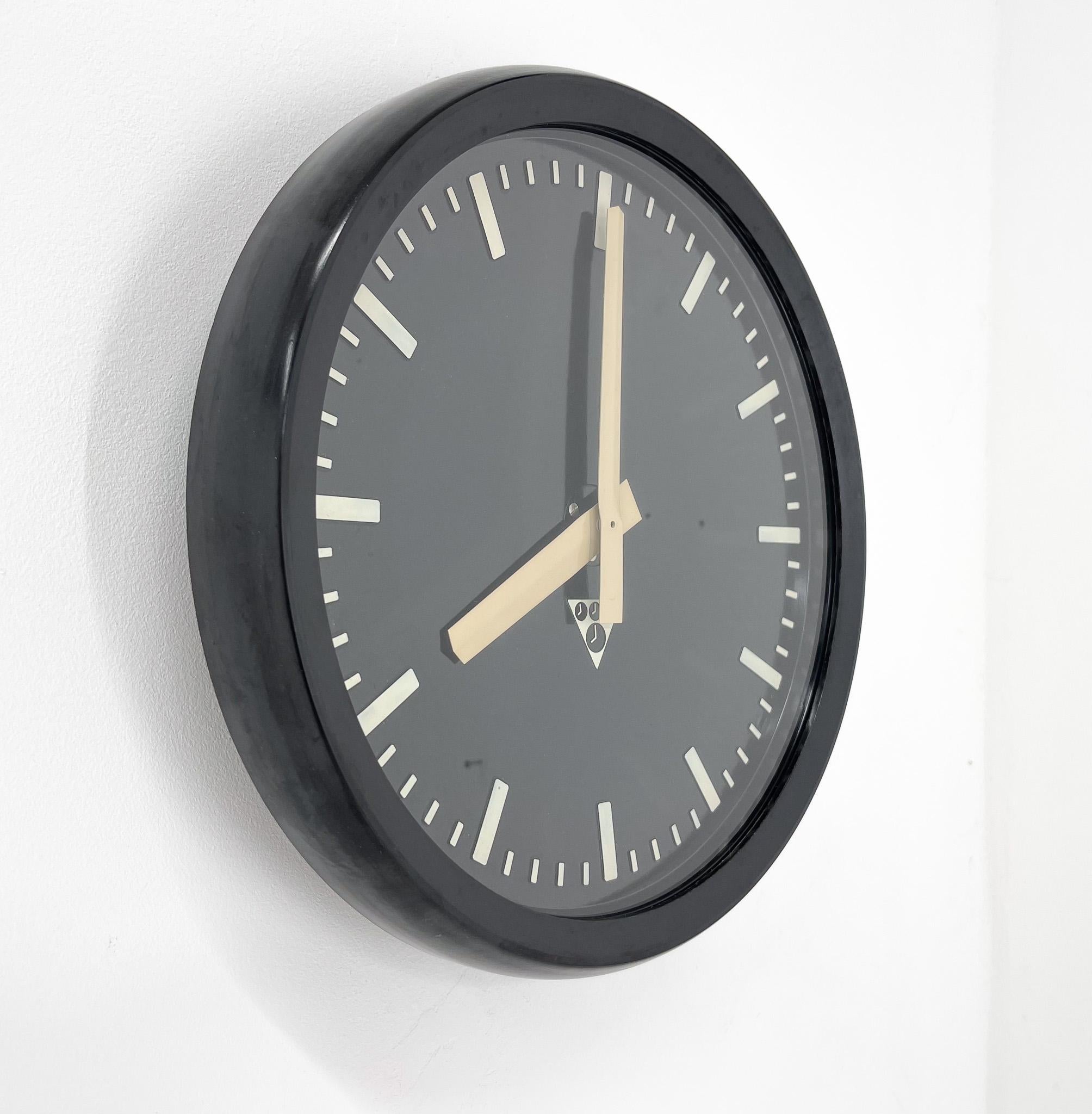 Horloge murale ronde vintage, en plastique noir et verre, fabriquée par le célèbre Pragotron en République tchèque. Nécessite une pile AA.