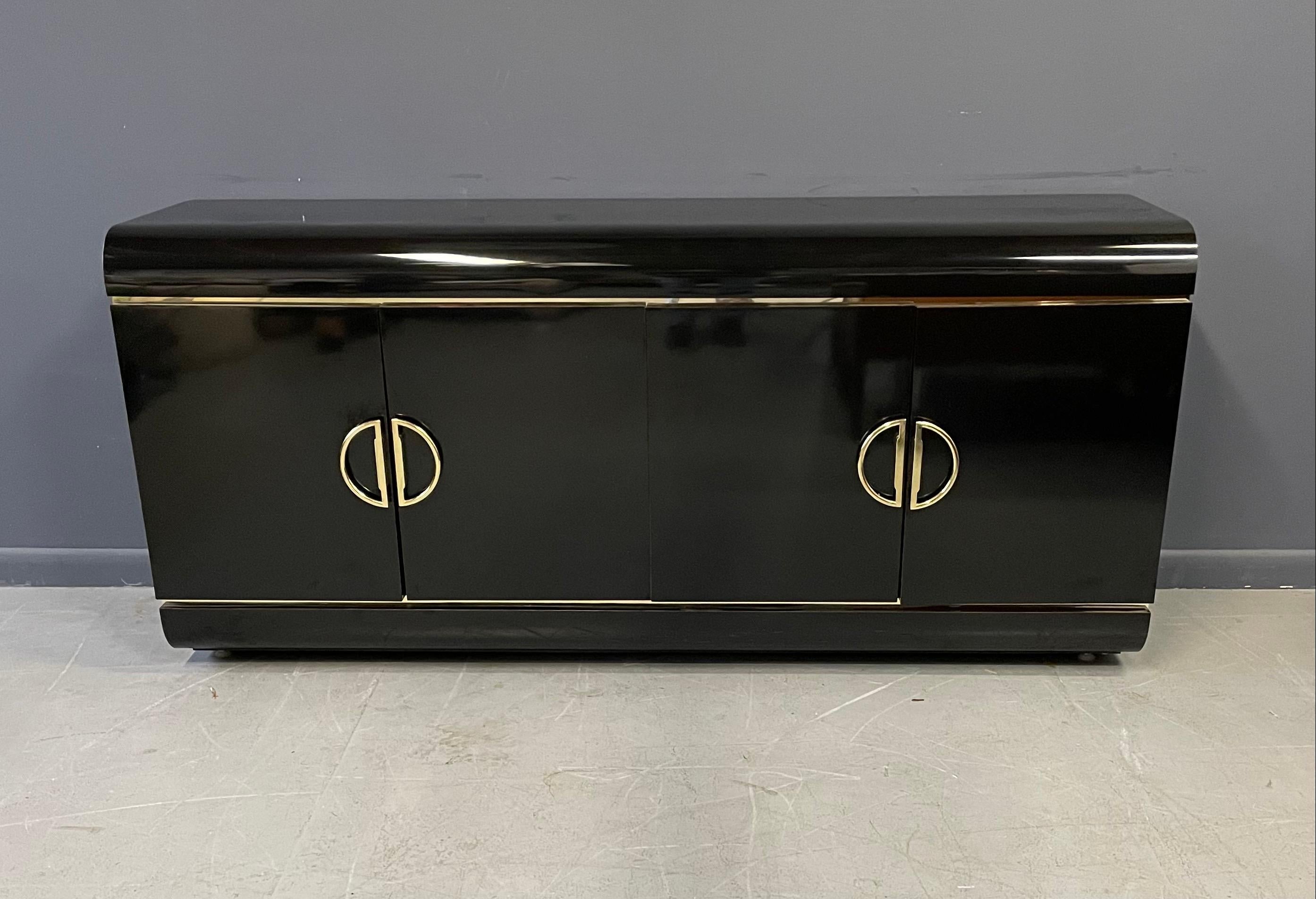 Credenza with brass trim and handles, one side has a drawer and the other side has one adjustable shelf.