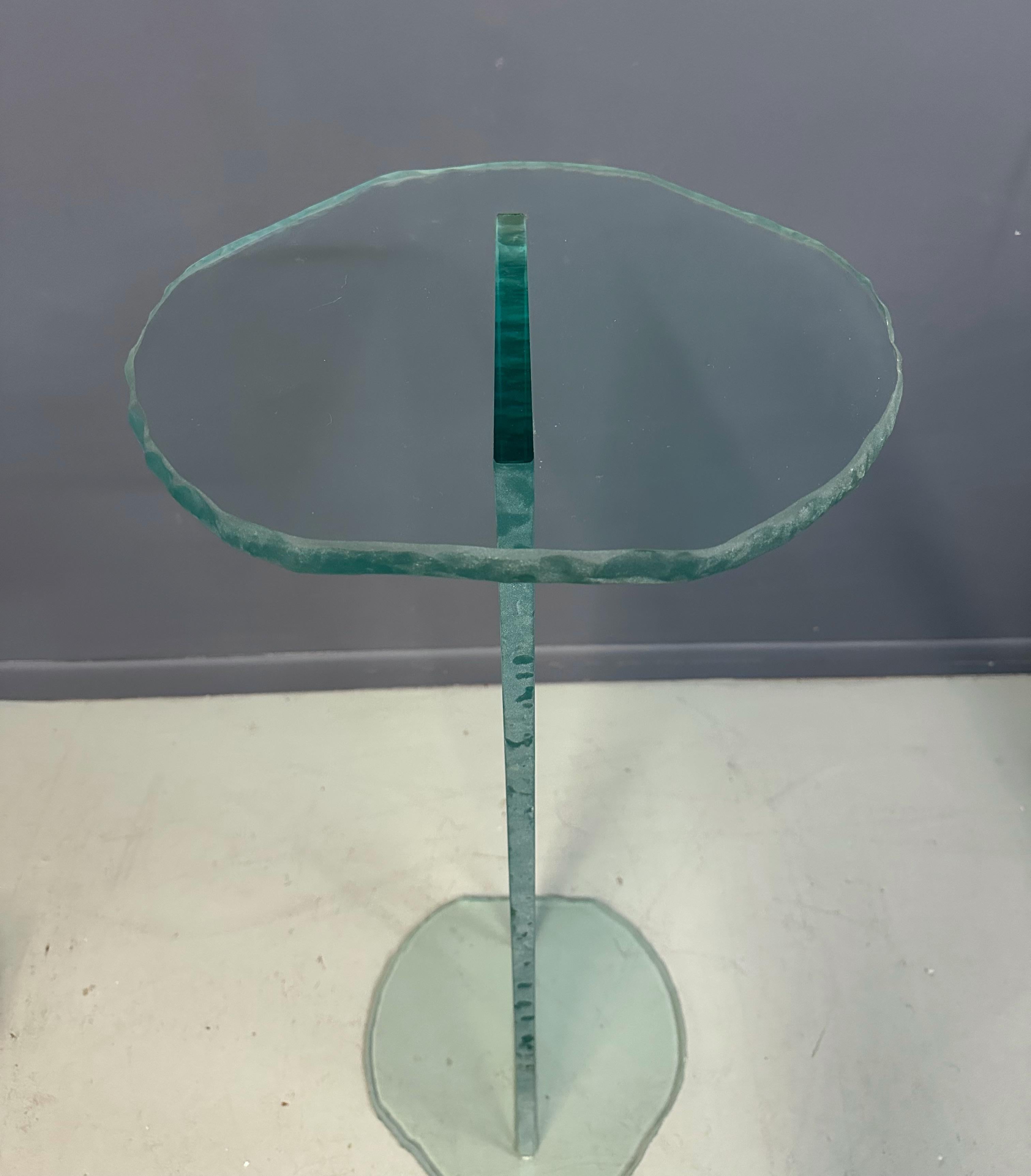 This 1990s Post Modern Rough Edge Glass Pedestal showcases a distinctive blend of rugged texture and refined form, characteristic of the postmodern design movement. Featuring thick, rough-cut glass edges, it offers a tactile contrast to its smooth