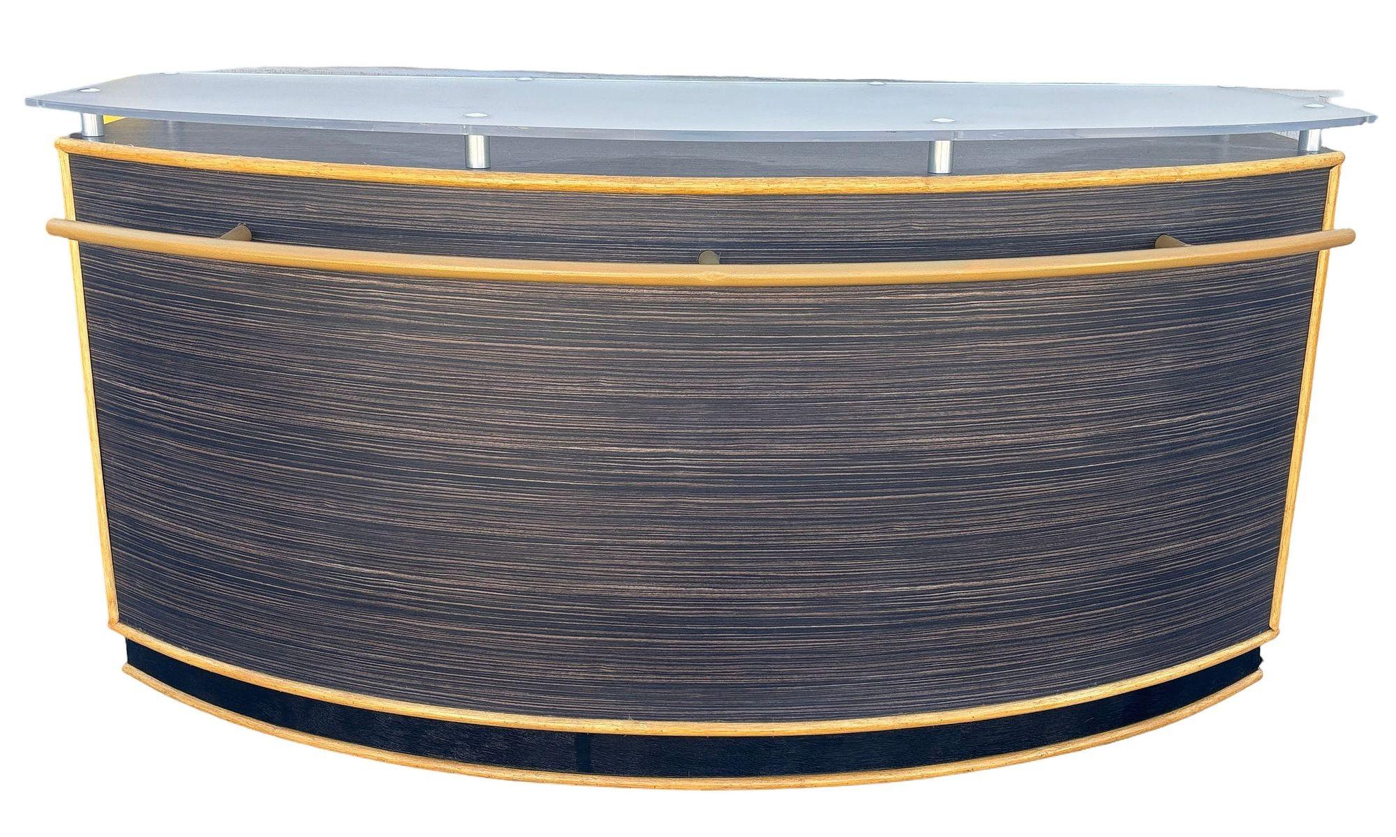 A striking postmodern dry bar or counter featuring a sleek curved form, smoked frosted plexiglass top, and elegant wood-grain finish. Restored and customized with rattan borders and brushed steel accents, this piece blends contemporary