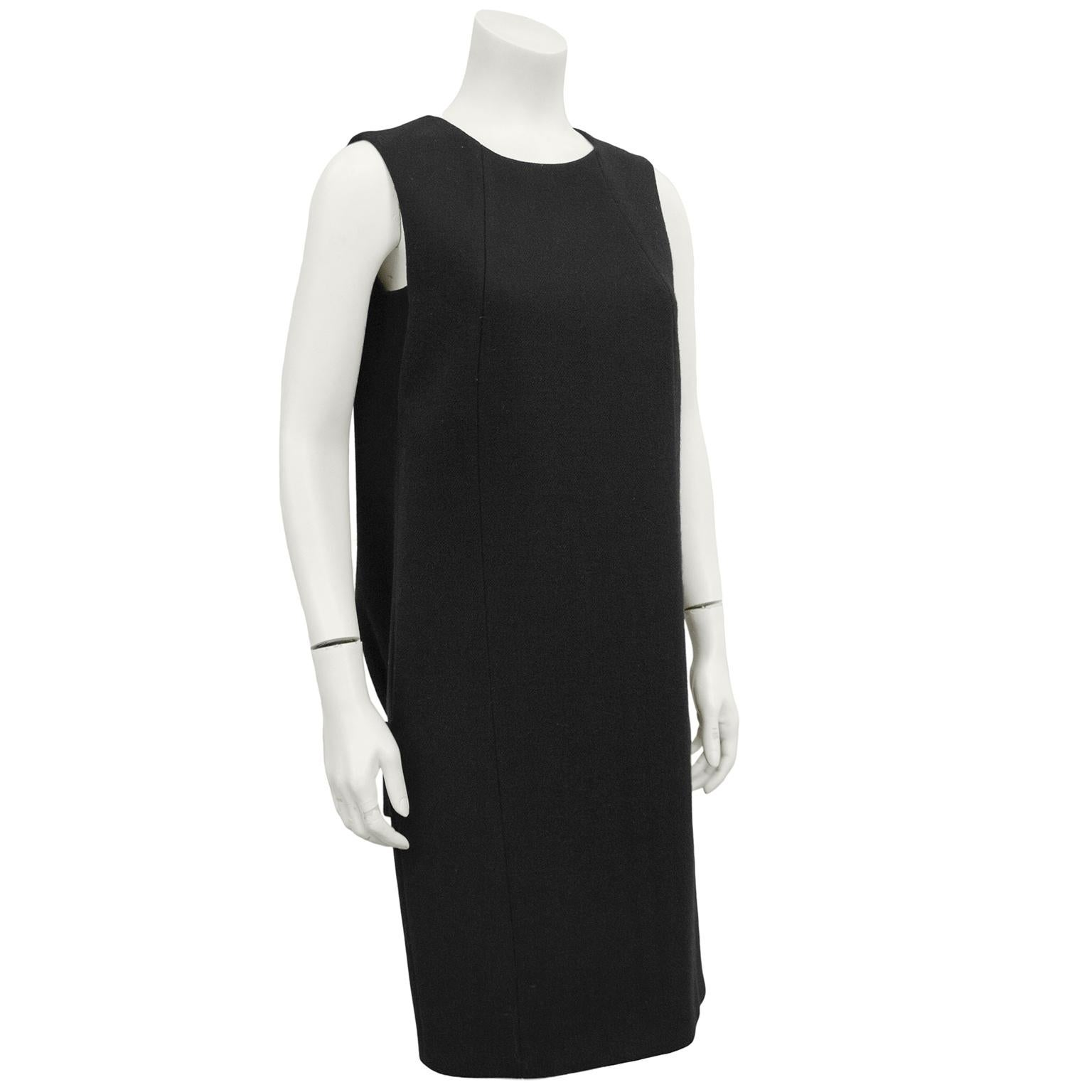 Stunning 1990s Prada black wool dress. Simple sleeveless from the front with two side seams. Back features a large inverted box pleat down the centre back with a wide drop waist half belt. Inspiration by early letter shaped Balenciaga silhouette.