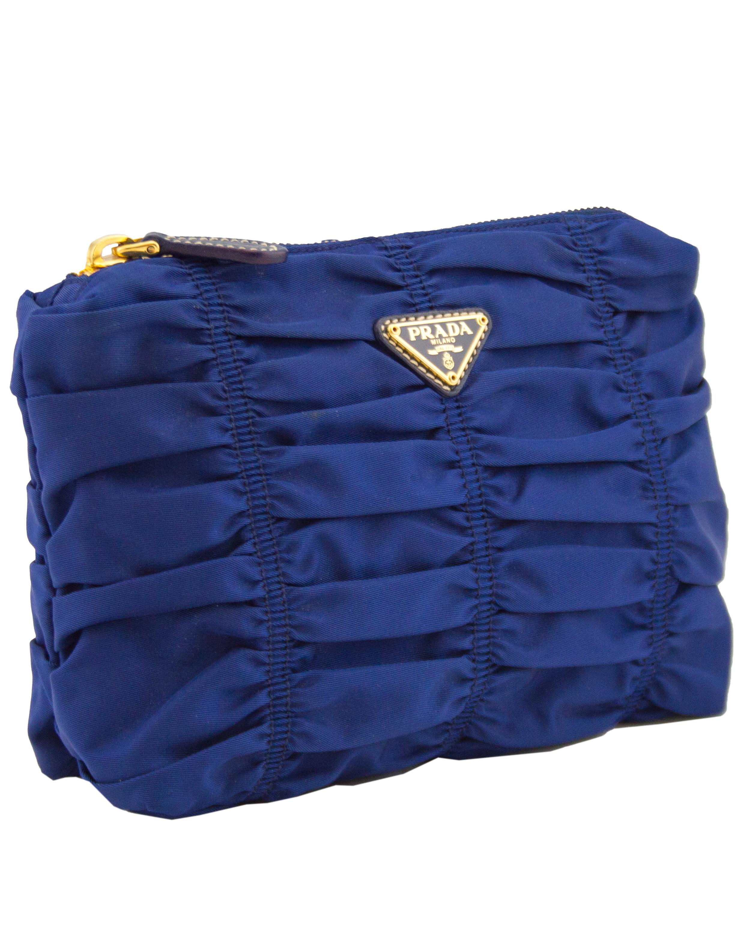 1990s Prada blue nylon clutch. Ruching throughout gives the bag texture. Iconic Prada triangle brand logo and goldtone zipper with blue leather pull tab. Black branded nylon lining. Works wonderfully as a clutch for a cocktail party, and great for