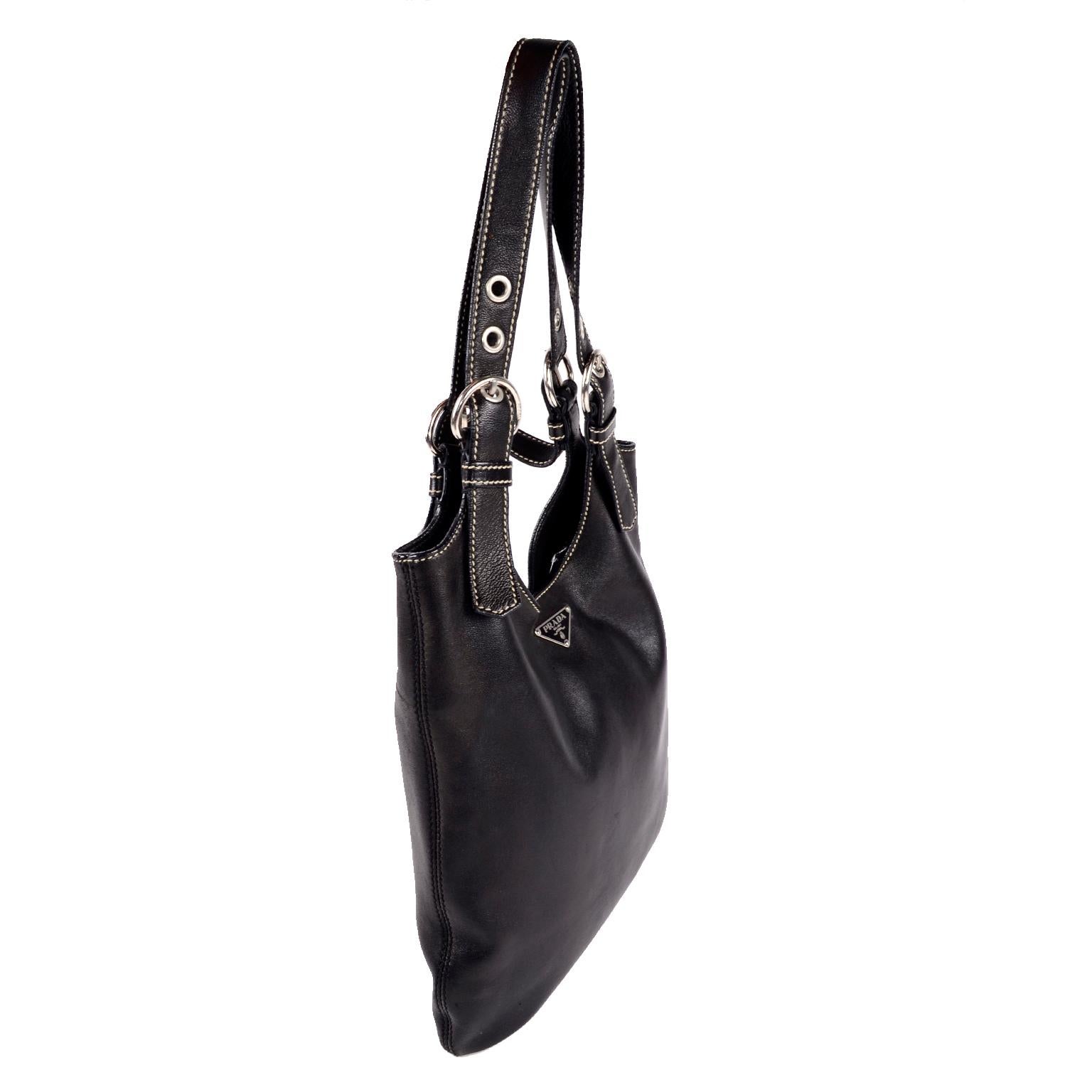 This is an incredibly soft, buttery black lambskin Prada hobo bag with silver hardware and the iconic Prada triangle nameplate.  The bag has white contrast stitching and Prada monogram lining.  This top handle bag has an interior side