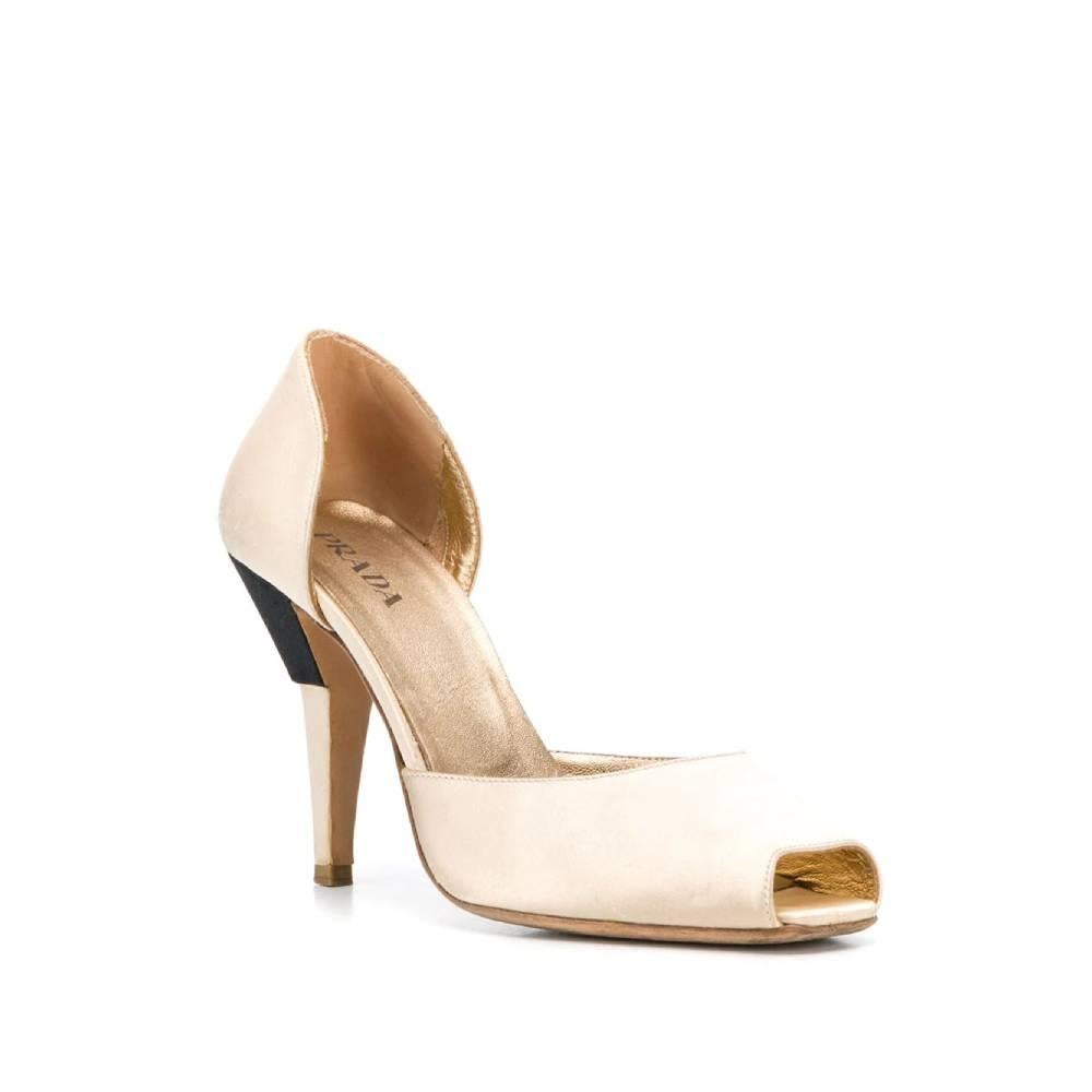 Prada ivory silk décolleté, with open square toe and sculpted high heel with black insert. Insole in genuine golden leather with logo

The item shows scratches and signs of wear on the silk.
Years: 90s

Made in Italy

Size: 38 EU

Heel height: 10