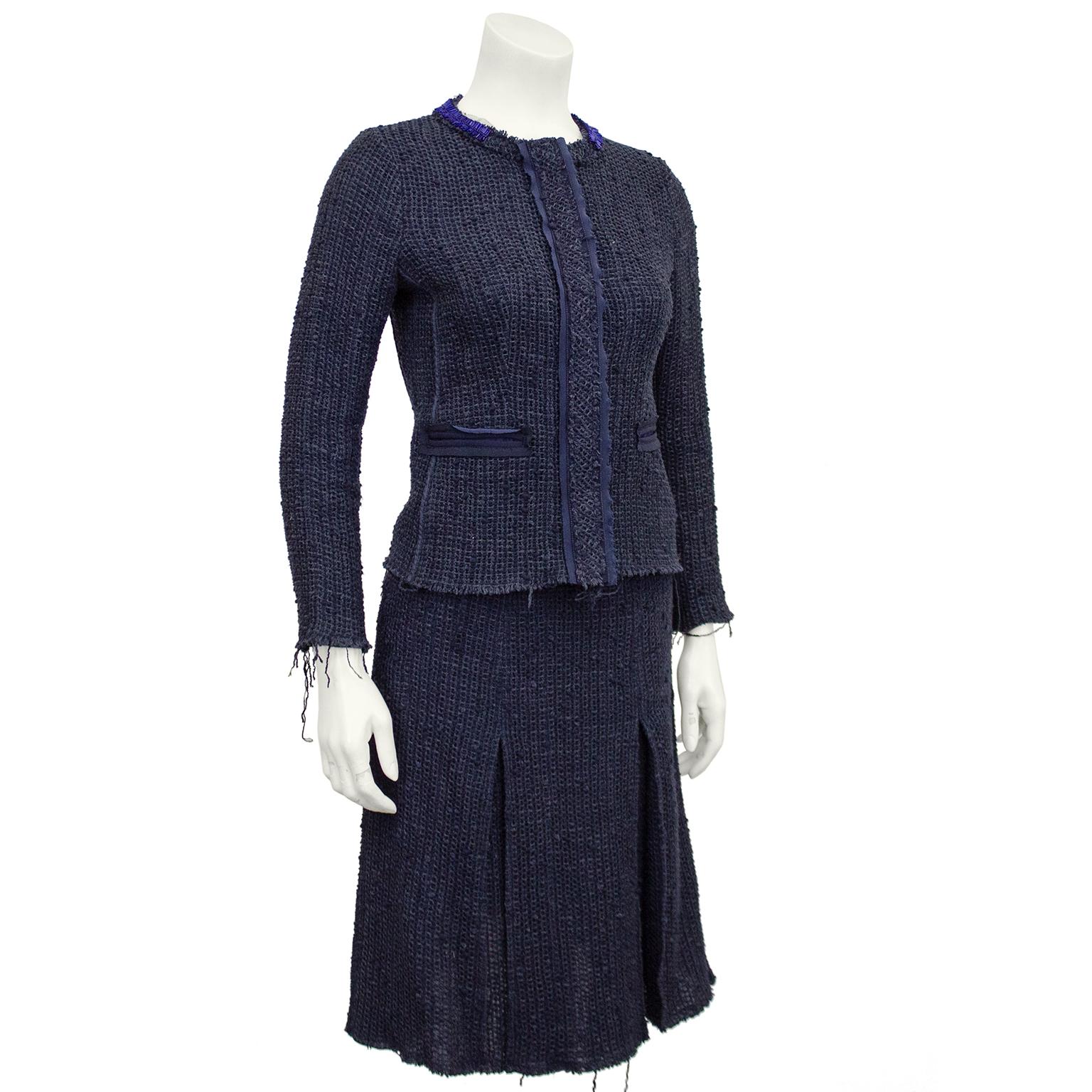 1990s Prada navy blue knit tweed skirt suit. Jacket features royal blue beaded embellished crew neck collar with a ribbon tie at nape of neck, creating the illusion of a beaded necklace over the suit. Two horizontal slit pockets bound in grosgrain