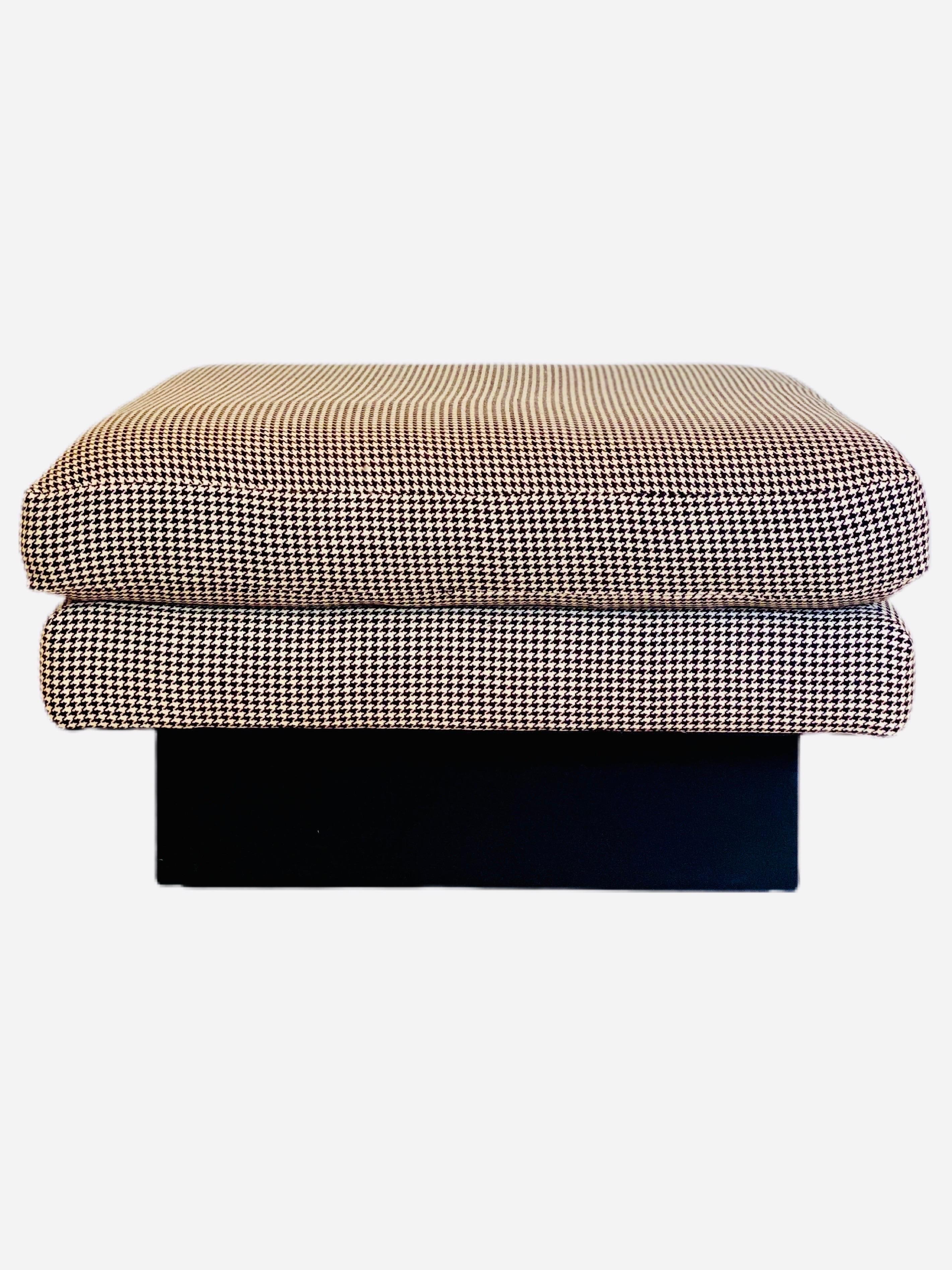 We are very pleased to offer a chic, large set of ottomans, circa the 1990s. A raised silhouette takes front stage in this fashionable duo. It starts at the base, an upholstered plinth in a black fabric sets the tone for an iconic symbol, the