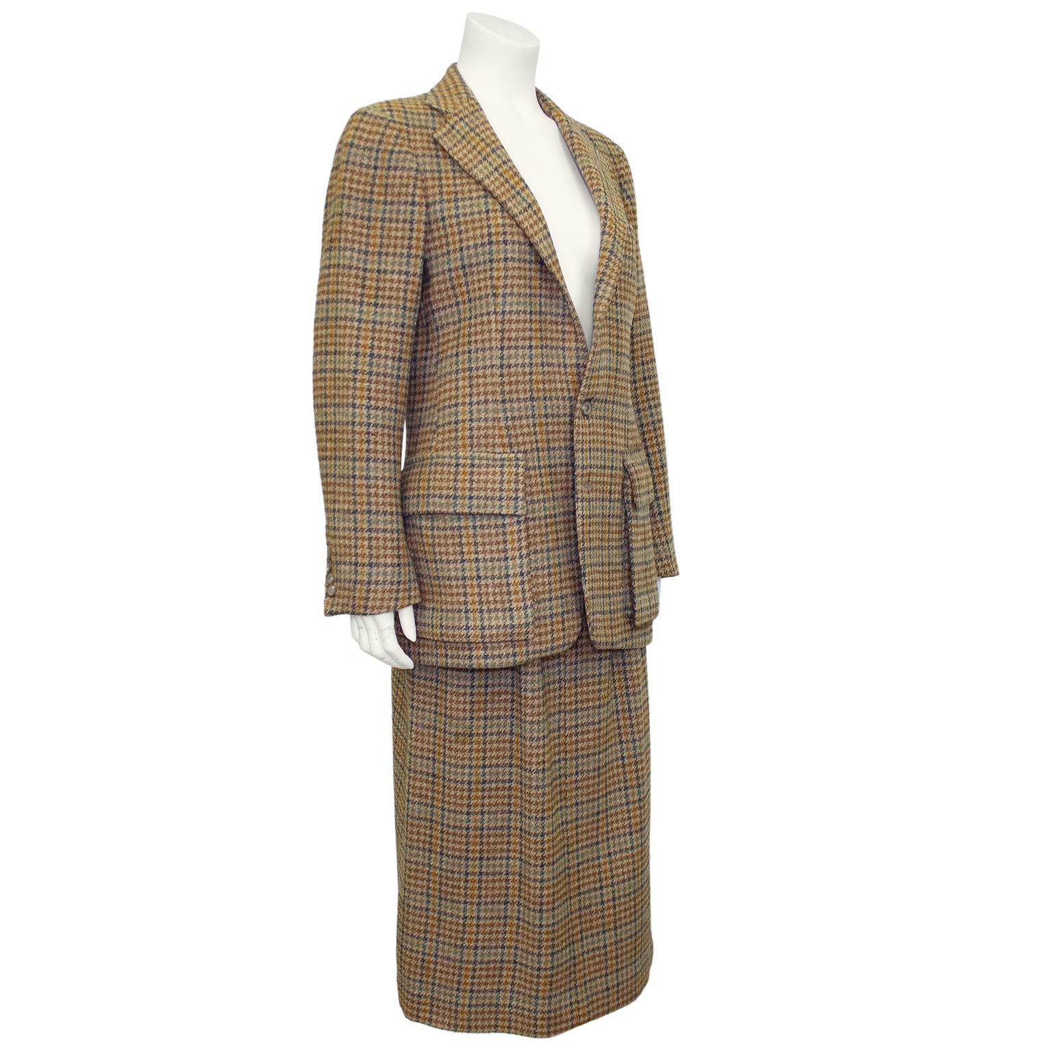 Classically preppy Ralph Lauren suit from the 1990s. Tan wool mini houndstooth with contrasting brown, navy, teal and caramel throughout. Hacking jacket features a notched collar, two button closure, four mini buttons at cuffs, a horizontal slit