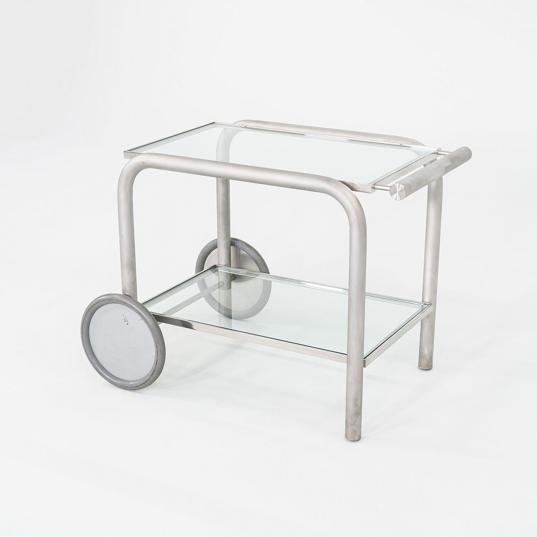 Questo è un prototipo di carrello da servizio o carrello da bar, progettato da A. Schultz per la sua Collectional 2002. Il telaio tubolare in acciaio inox ha una superficie opaca e spazzolata, mentre le ruote sono in plastica grigia e gomma. Le due