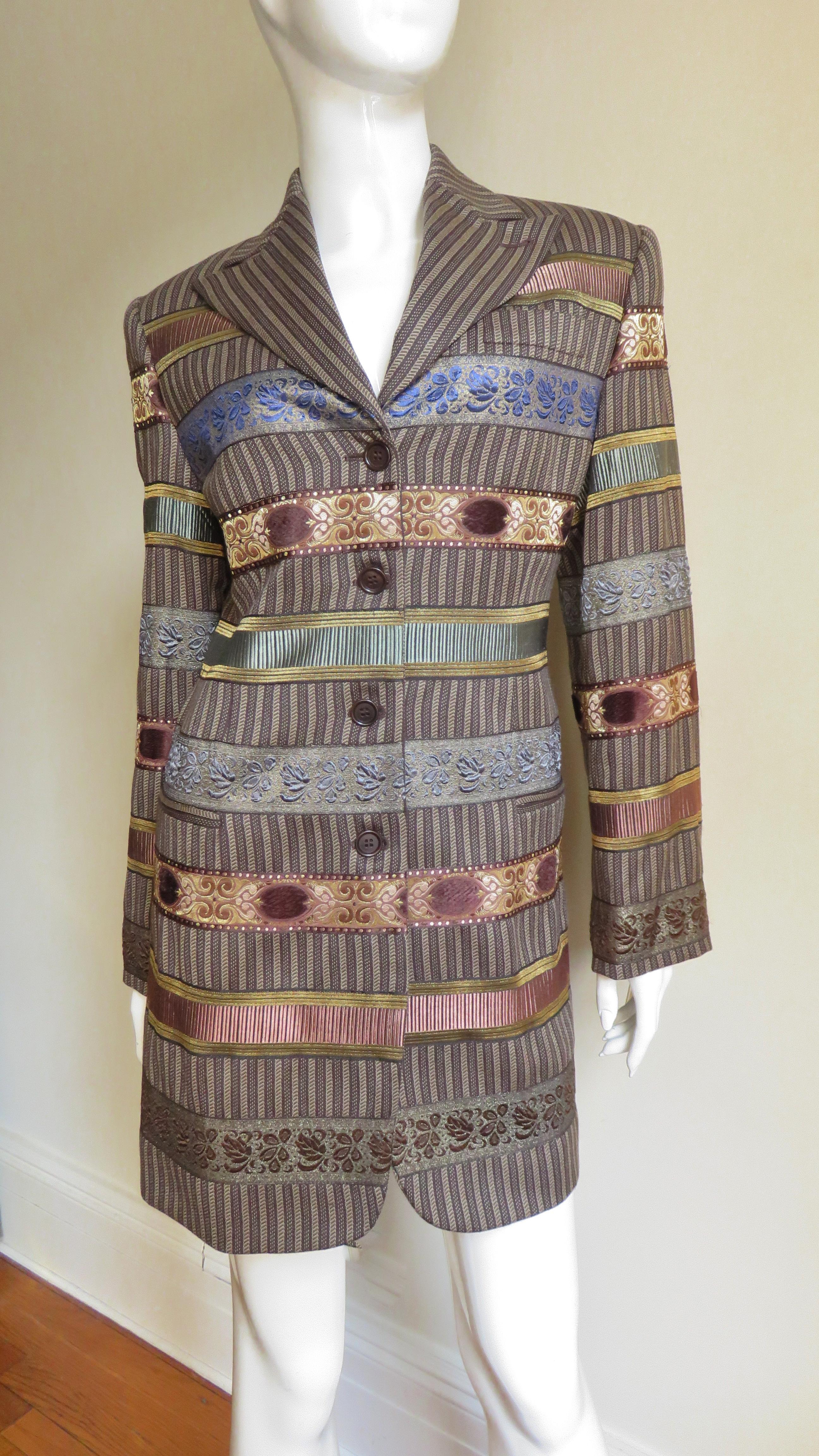 This is an incredible brown striped jacket by Romeo Gigli.  It is long, single breasted with brown buttons, long sleeves and a notched lapel collar.  It is a standout with rows of intricately embroidered and tapestry ribbon in browns, gold and muted