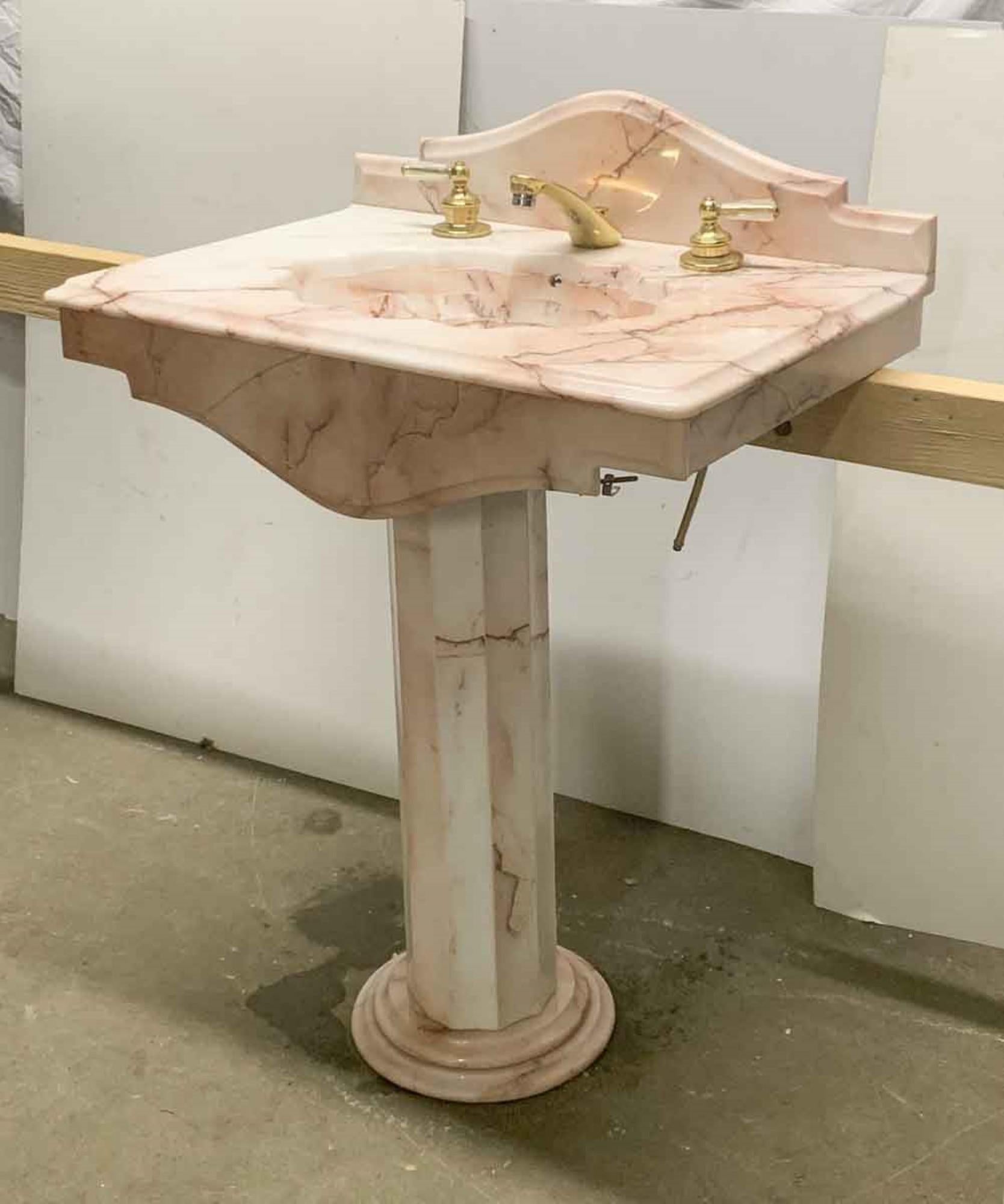 1990s solid rose colored marble pedestal sink with the original hardware. Features an arched backsplash. This can be seen at our 400 Gilligan St location in Scranton. PA.