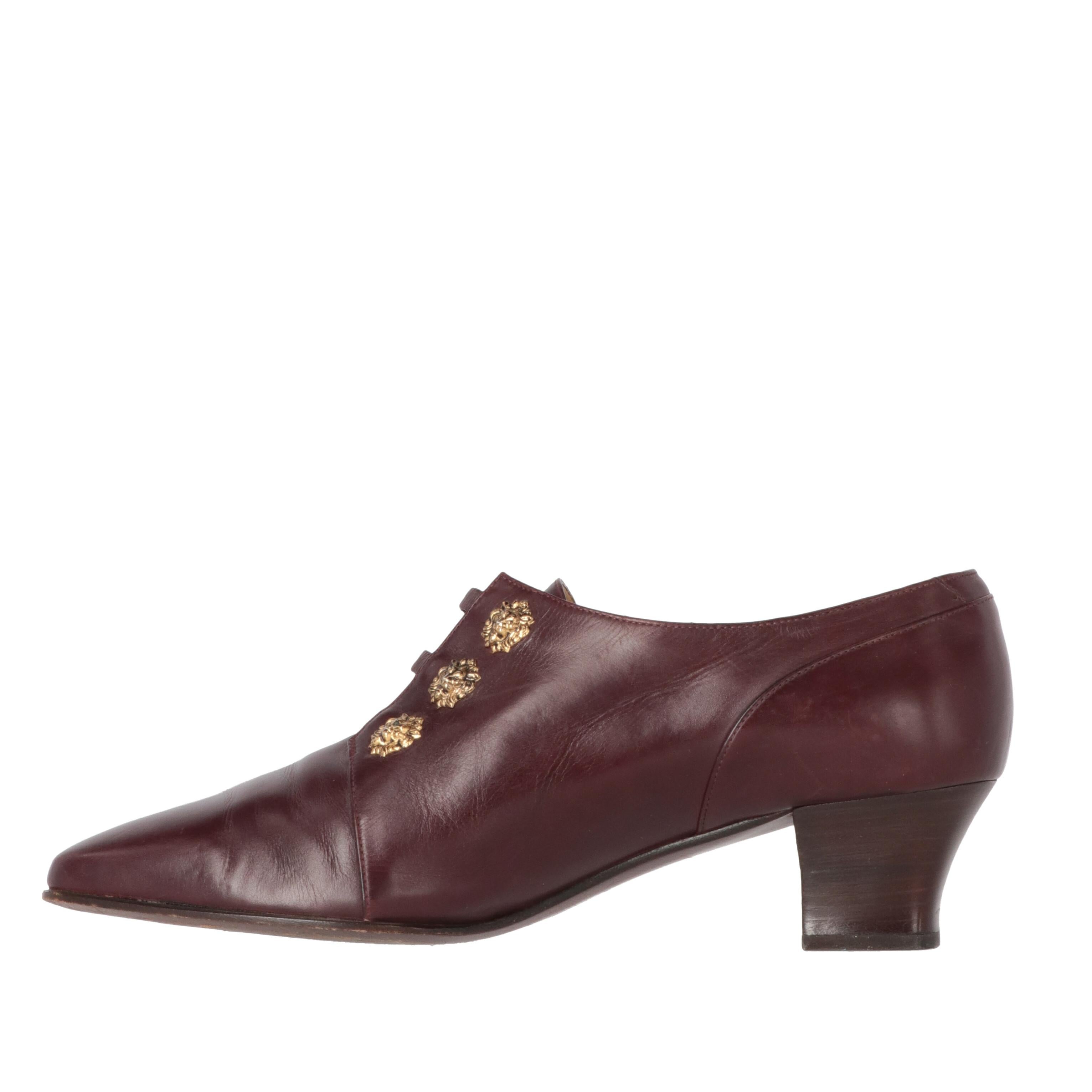 Sergio Rossi burgundy genuine leather shoes. Slightly pointed toe with wooden low heel in Louis XV iconic style. Three slightly elasticated straps on the instep and two rows of lion's head shaped decorative studs in gold-tone metal.

The item shows