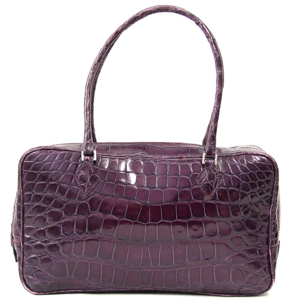 Extremely chic crocodile leather purse in deep, glamorous purple. Made by the famous Italian leather brand Sirni in the 1990s, it closes with a zip and has three pockets in the inside with a brilliant, vidid purple lining. Handles are very thin and