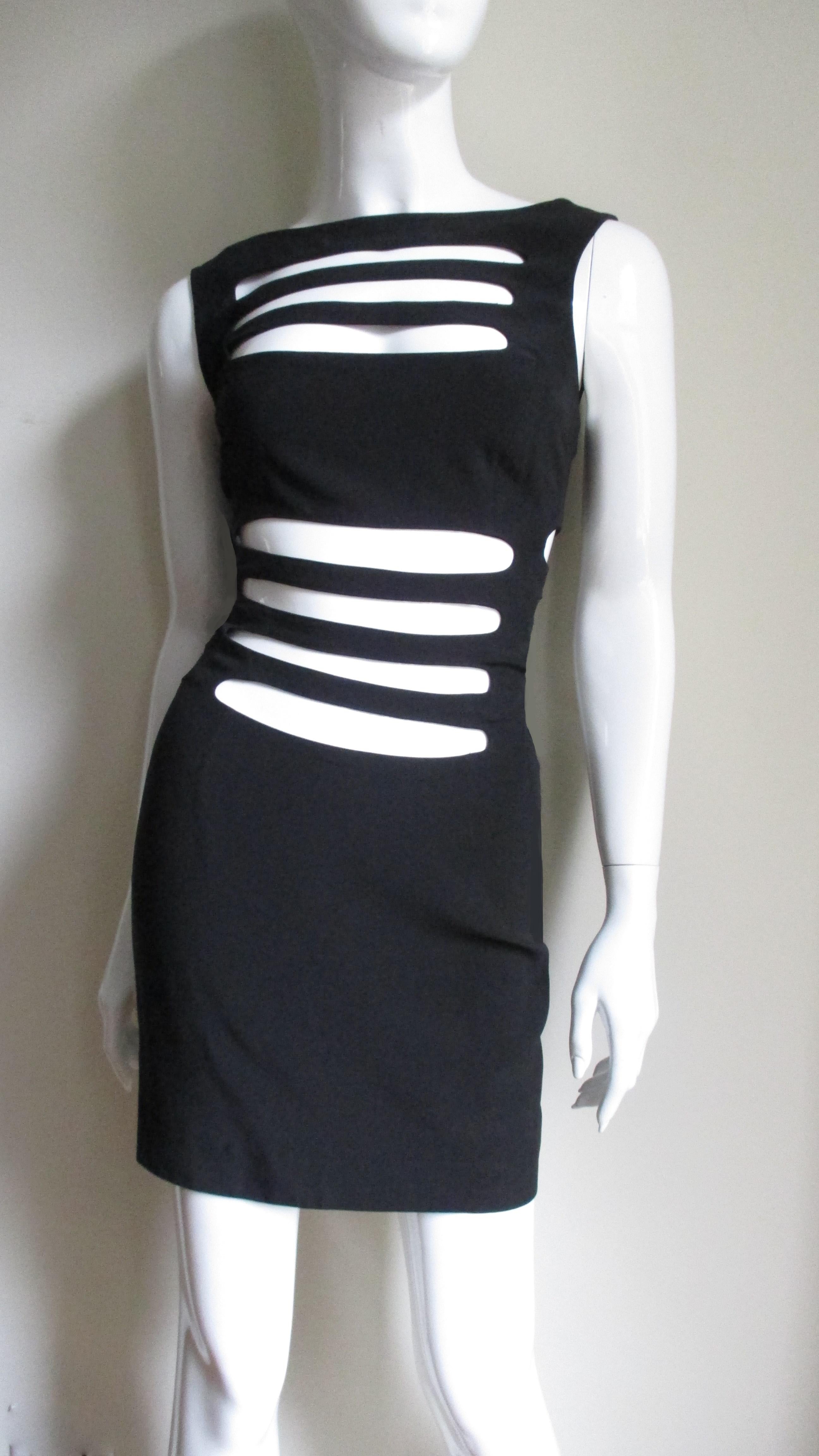 An avant garde black dress from French designer Sophie Sitbon.  It is a simple sleeveless crew neck dress covered in long horizontal cutouts across the midriff, upper chest and sides.  The back has a scoop neckline and has no cutouts.  It is unlined