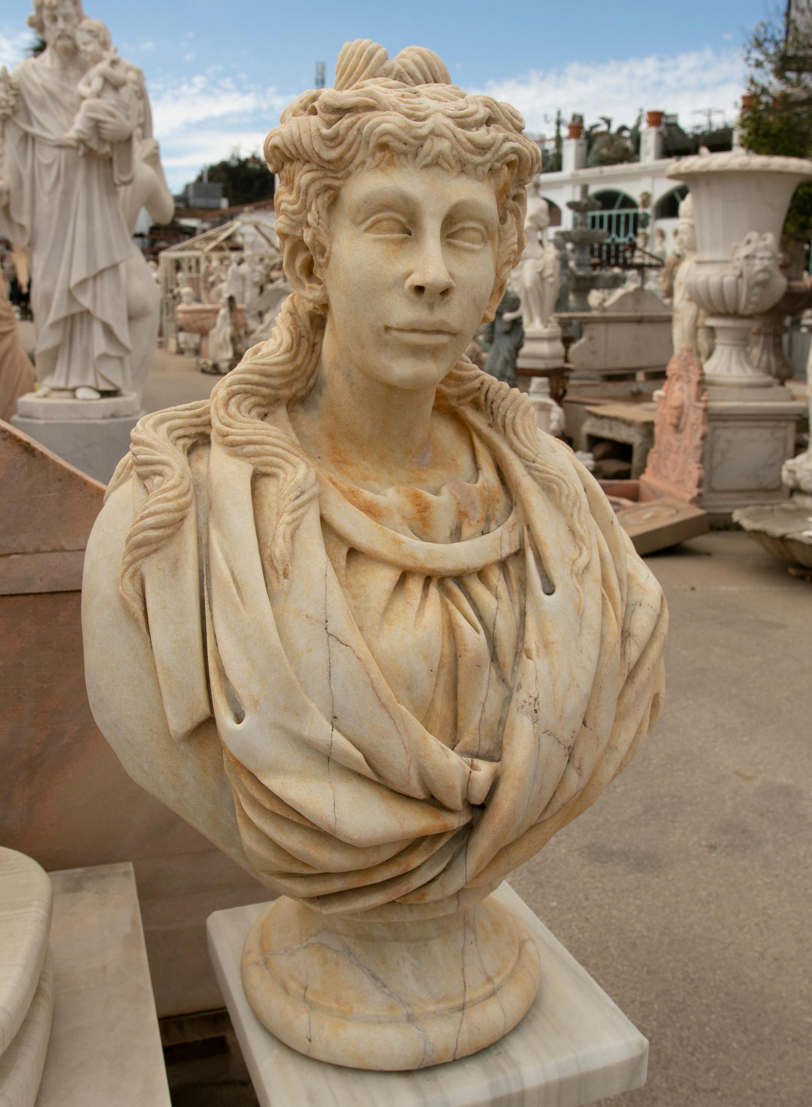 1990s Spanish hand carved aged Macael white marble bust of a Roman woman wearing a stola tunic.