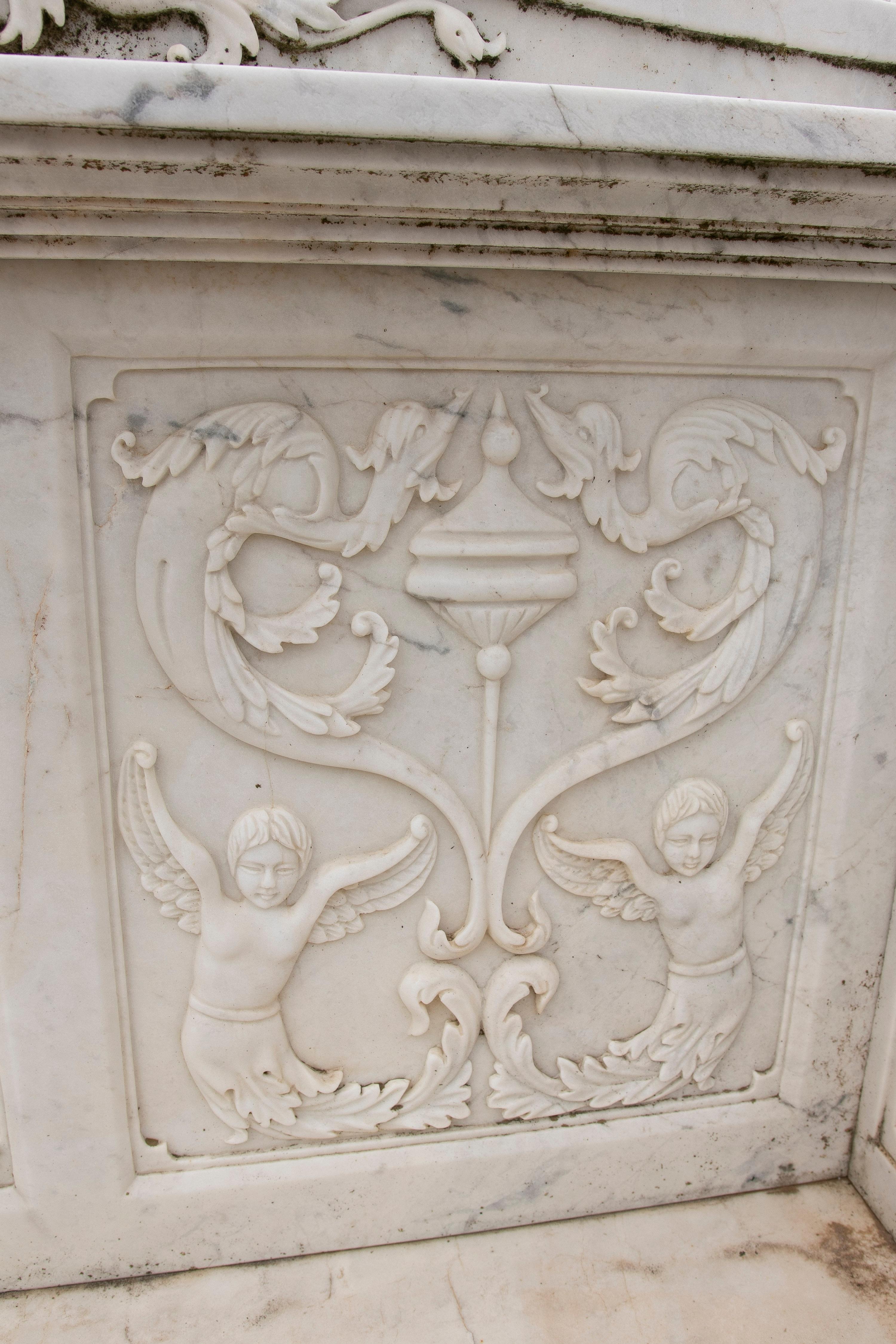 1990s Spanish hand carved Carrara white marble 2-seater garden bench in Italian Renaissance style, with ornate cherubs and plant relief decorations.