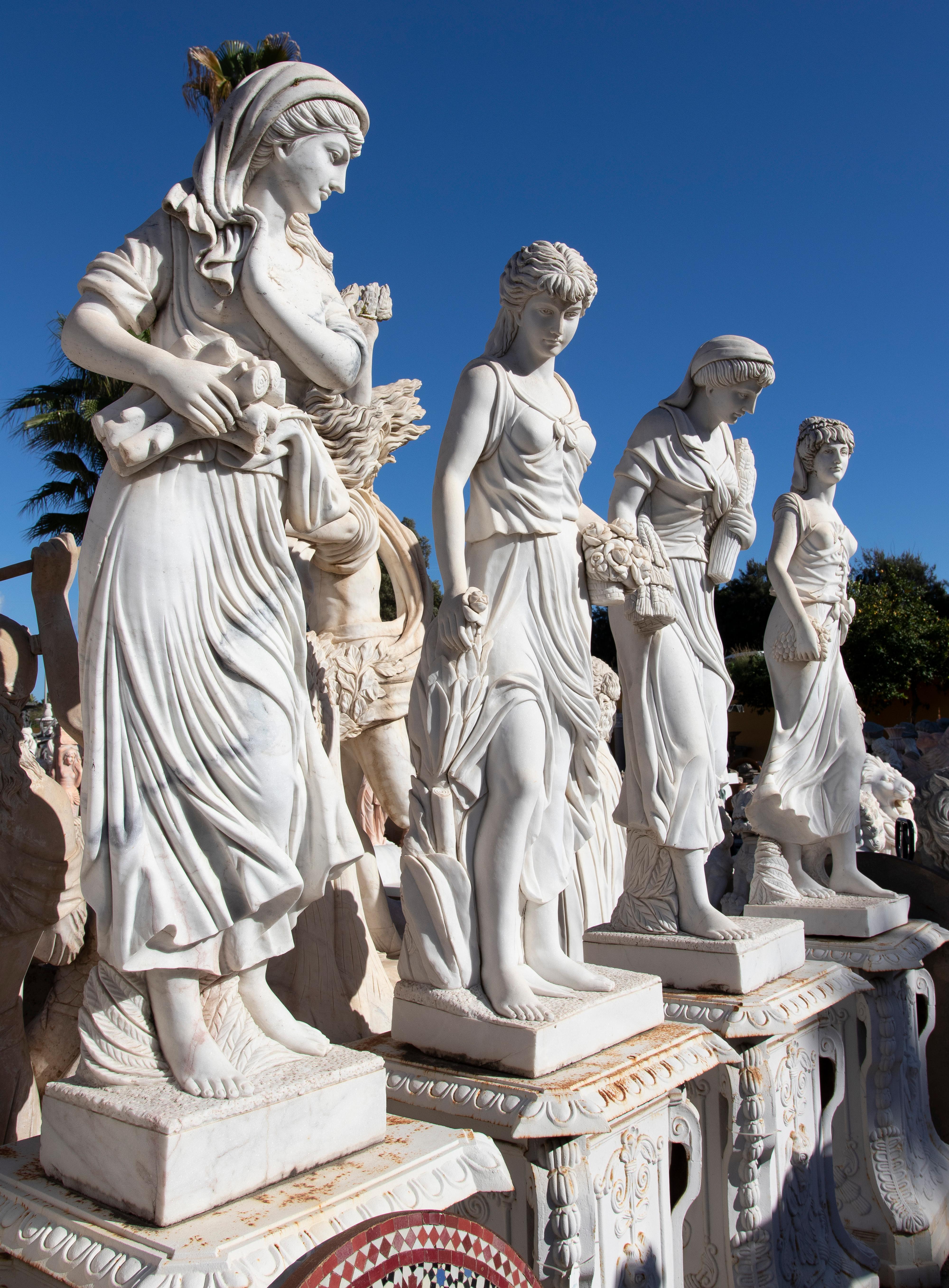 1990s Spanish hand carved Carrara white marble classical set of Four Seasons, where each statue is an allegory, starting with winter on the left, followed by spring, summer and finally, autumn.