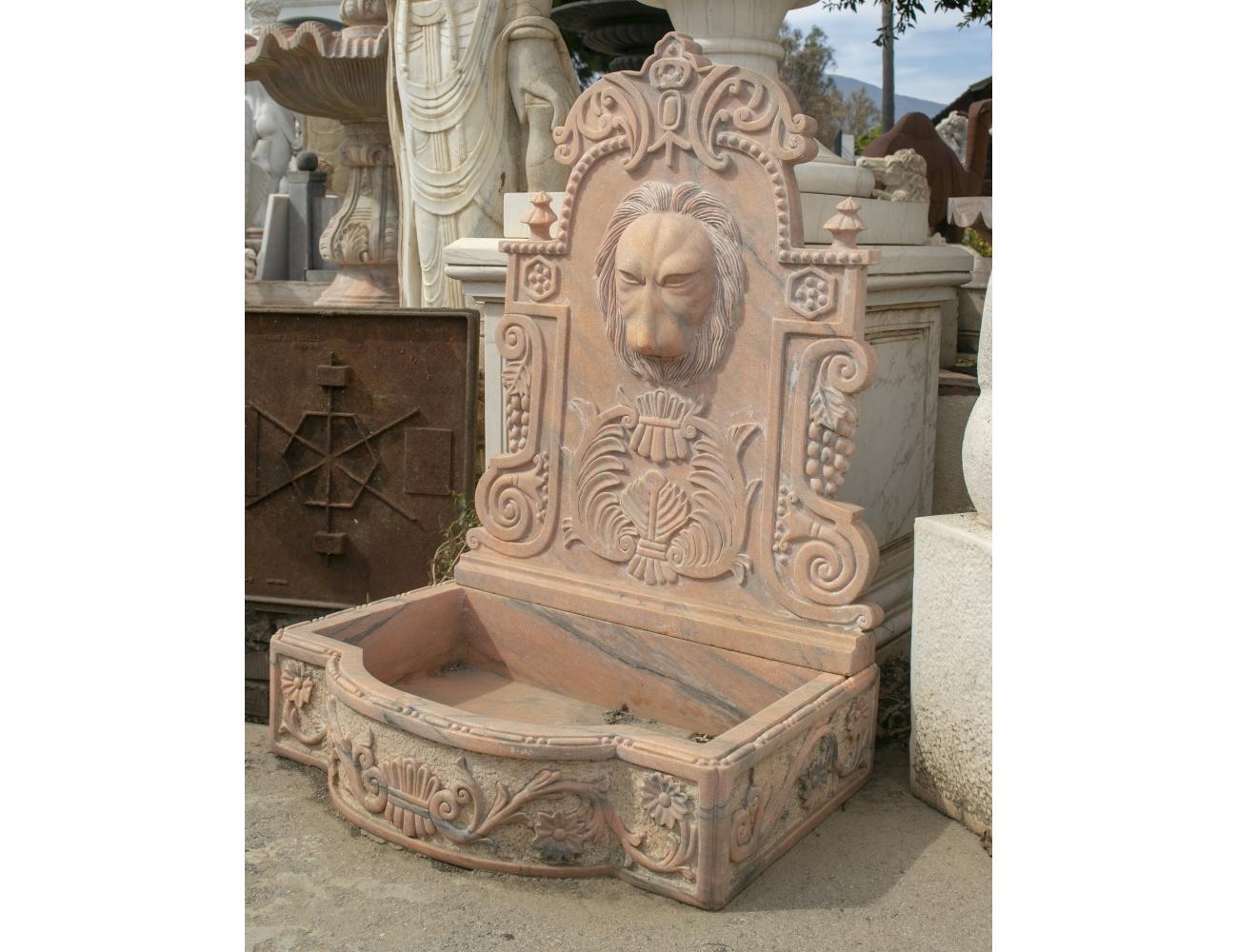 Petit 1990s Spanish hand carved aged pink Rosetta marble wall fountain.

It is composed of two parts, a pediment with a lion head mascaron spout and a one piece pool surround trough.