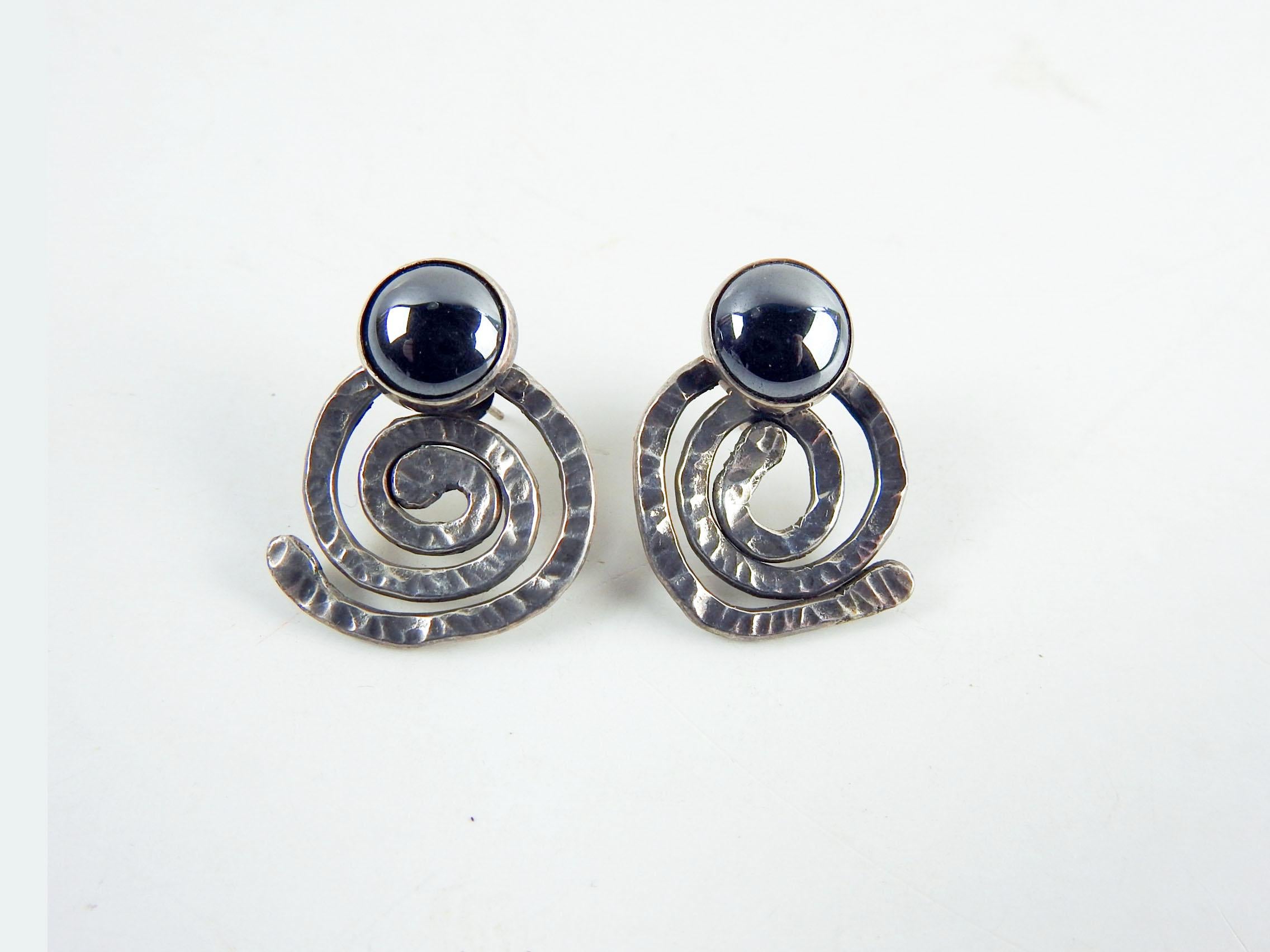 Artist studio hand wrought sterling silver and hematite earrings by Linda Thompson. Circa 1990's, sterling post, bezel set hematite cabochon stone, hammered finish. Overall patina, very good condition.