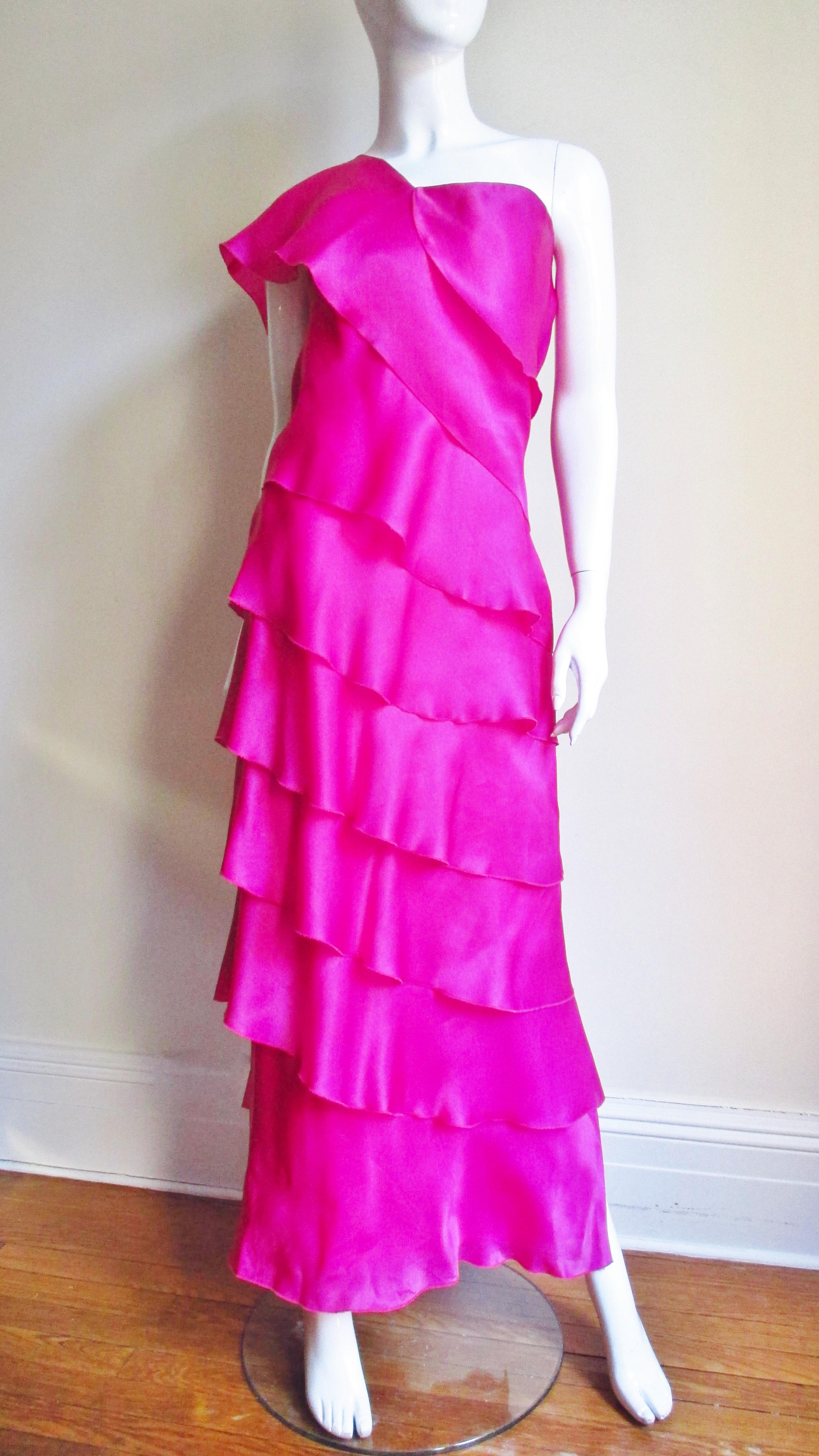 A gorgeous bright pink silk gazar gown by Jackie Rogers.  It has a one shoulder boned bodice with angled rows of silk wrapping around the dress to the hem.  It is lined in matching silk, has a side zipper, side slit and comes with a matchless