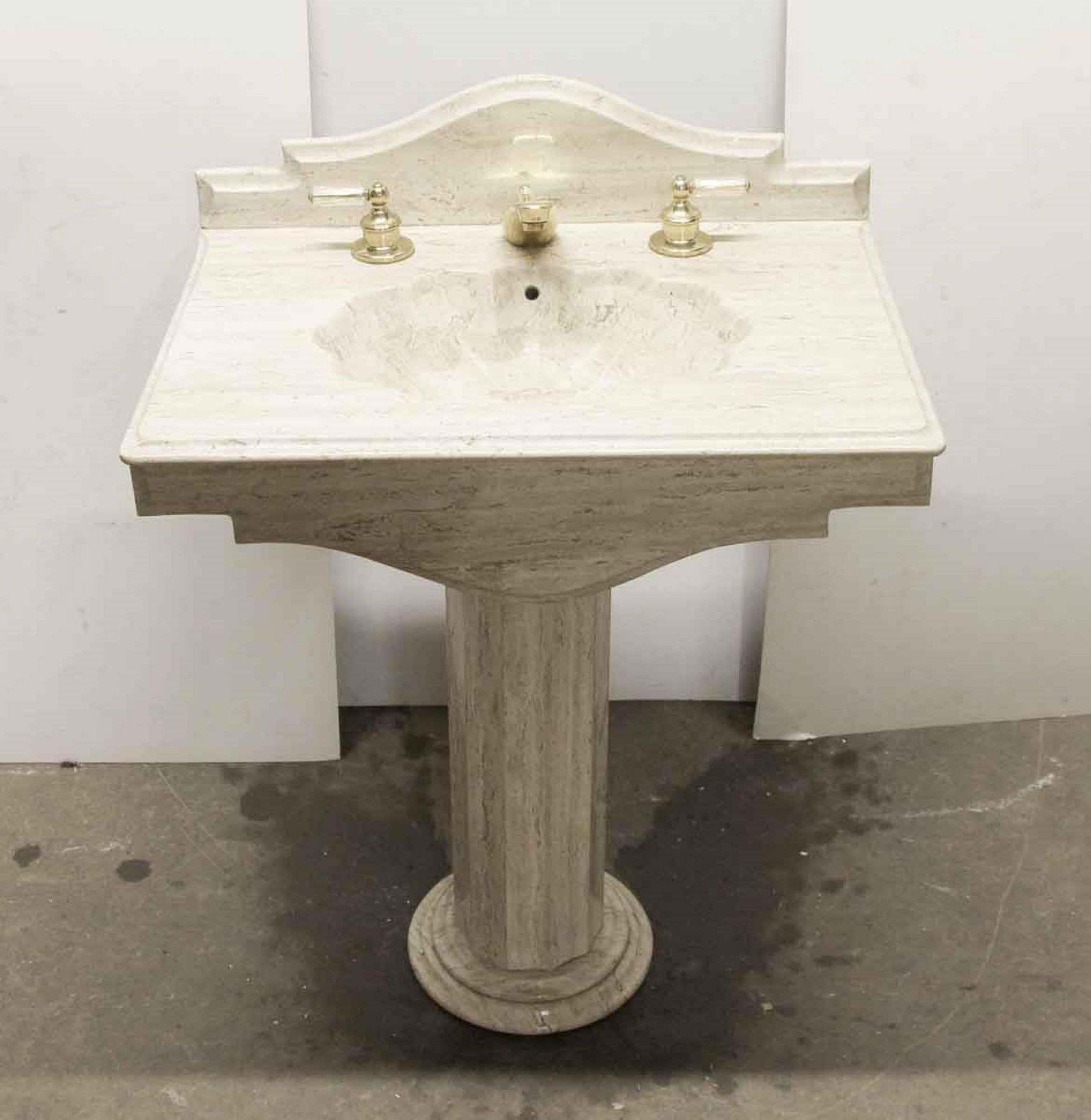 This is a multi-toned tan carved sink basin from the 1990s. The basin is designed with a seashell shape, with a further seashell design inside the bowl itself. The hardware is original, a clear plastic design covers the brass handles and top of