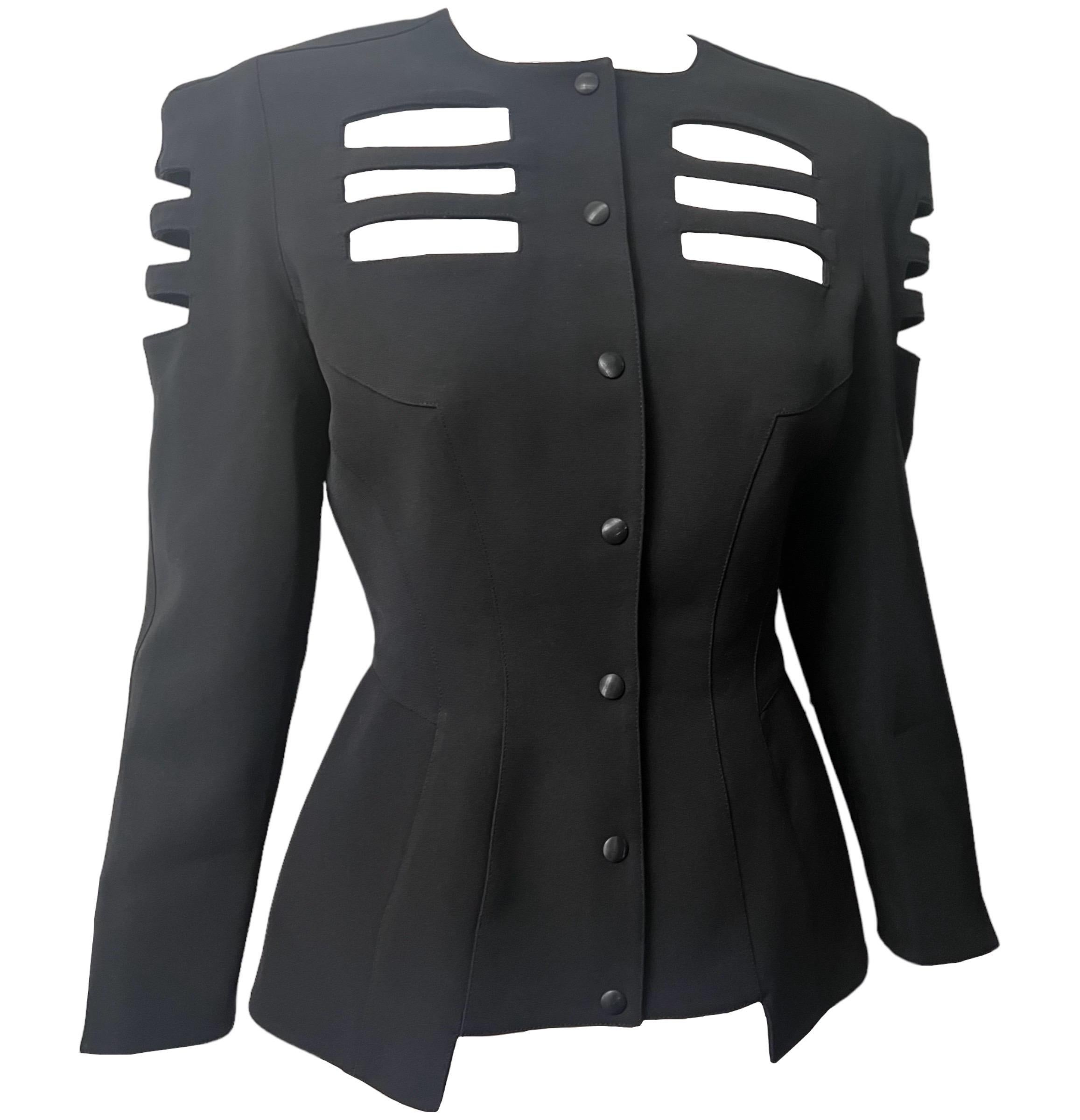 Schwarze Jacke von Thierry Mugler aus den 1990er Jahren mit drei Reihen rechteckiger Ausschnitte auf der Brust, den Oberarmen und der hinteren Mitte. 
Quadratischer Ausschnitt.
Schulterpads.
Druckknopfverschluss vorne.

Zustand: Durchgehend in sehr