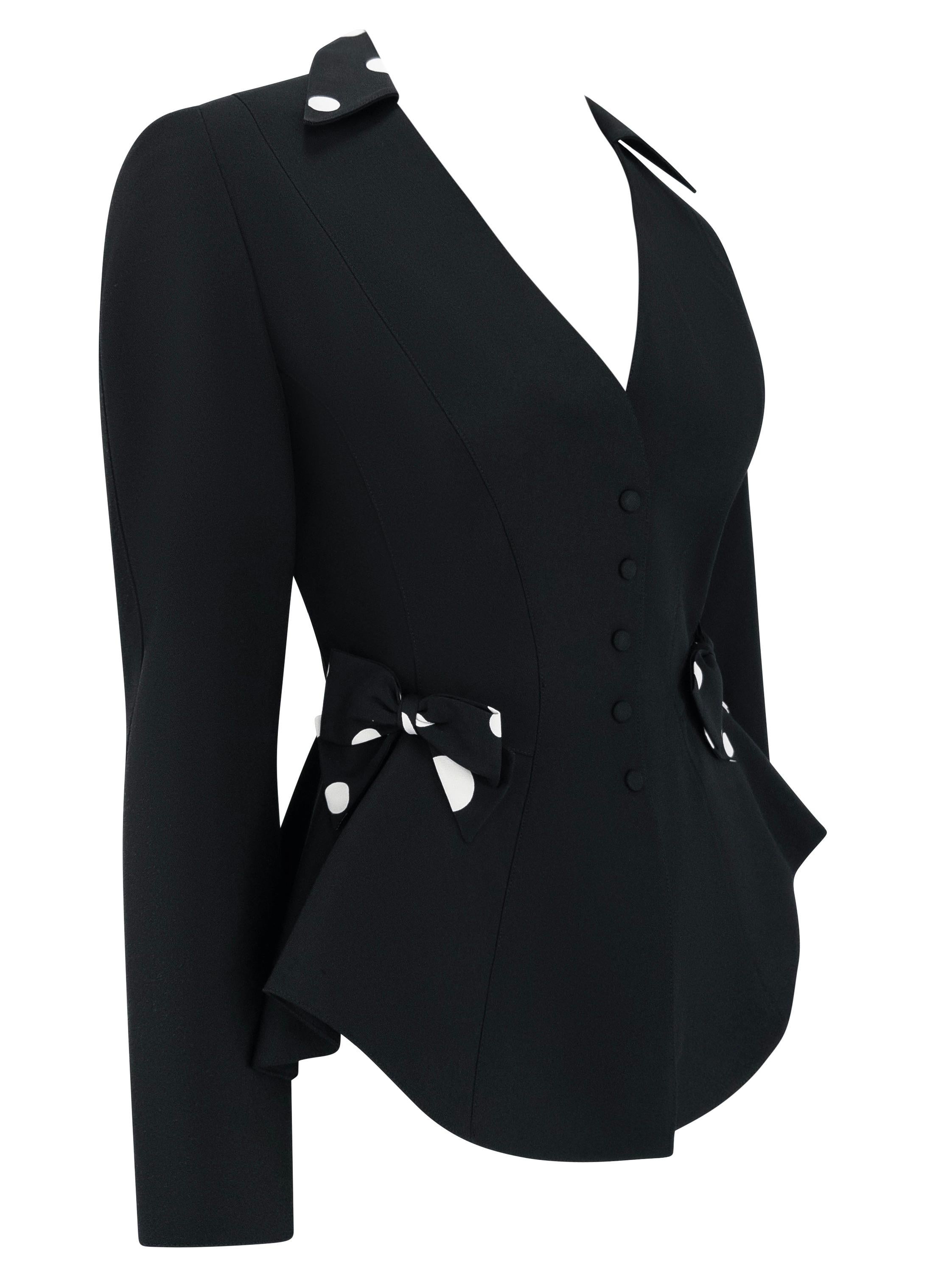 Datant des années 1990, ce blazer noir sculpté de Thierry Mugler présente une silhouette très ajustée aux courbes exagérées. Le design est accentué par des nœuds ludiques à pois noirs et blancs sur chaque hanche et par des détails de tissu assortis