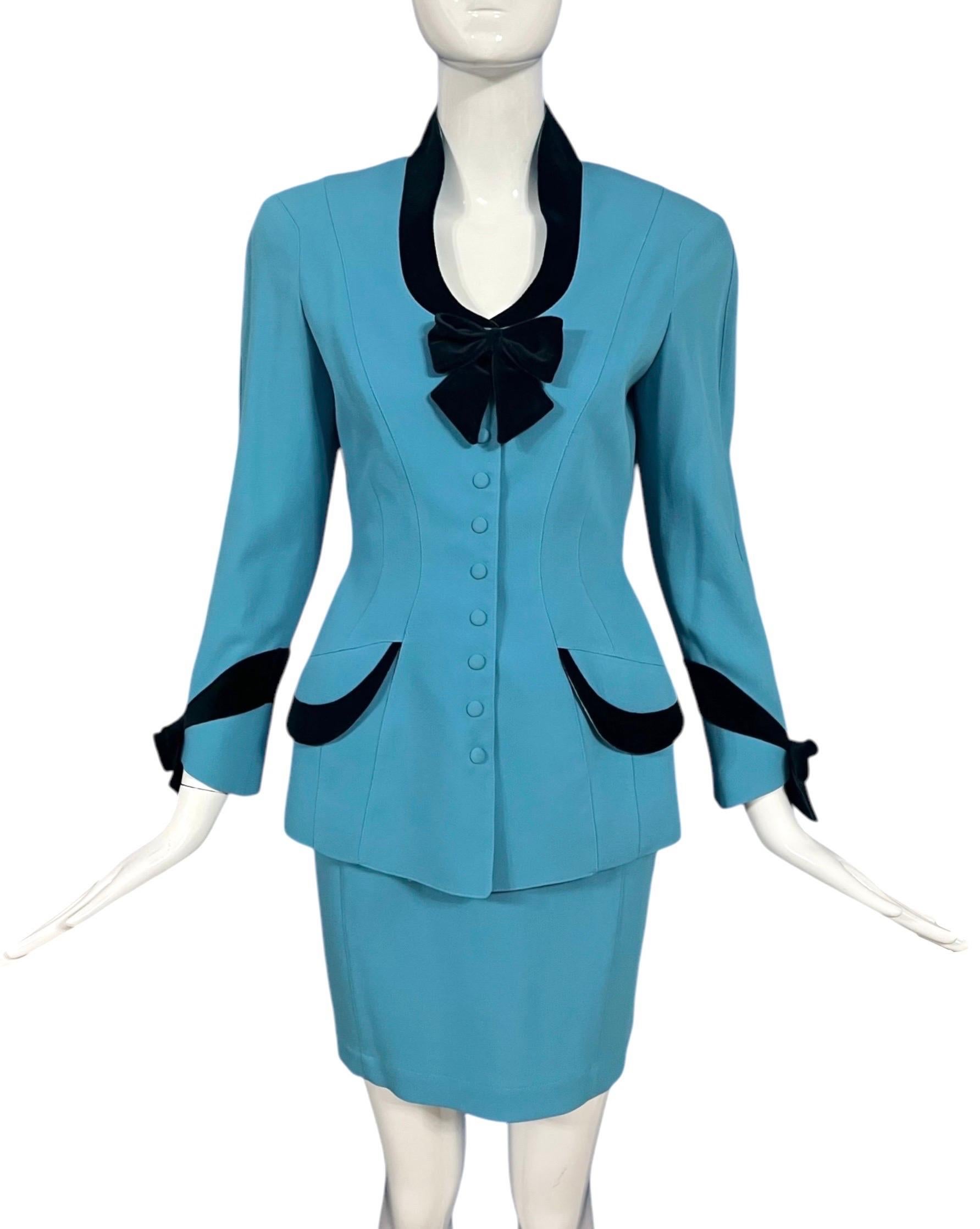Dieser auffällige Anzug von Thierry Mugler aus den 1990er Jahren zeichnet sich durch eine kühne, strukturierte Silhouette in einem leuchtenden Himmelblau aus. Ein auffälliges Detail ist der dunkelblaue Samtbesatz, der den Ausschnitt umrahmt und