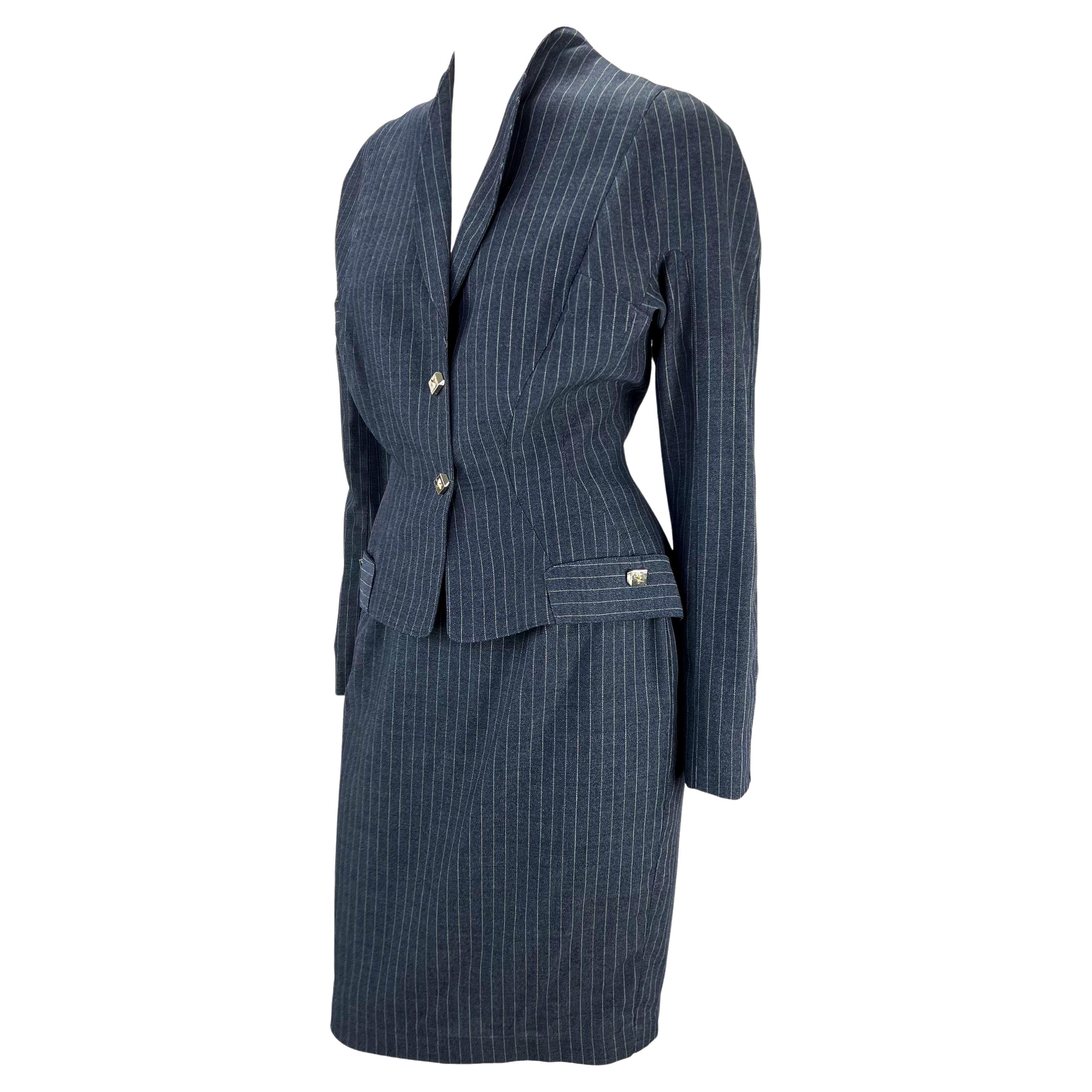 Presenting a sculptural pinstripe Thierry Mugler skirt suit, designed by Manfred Mugler. From the 1990s, this suit features masterful design and tailoring. The blazer features sculptural curved faux pockets which extenuate the hips. Both the skirt