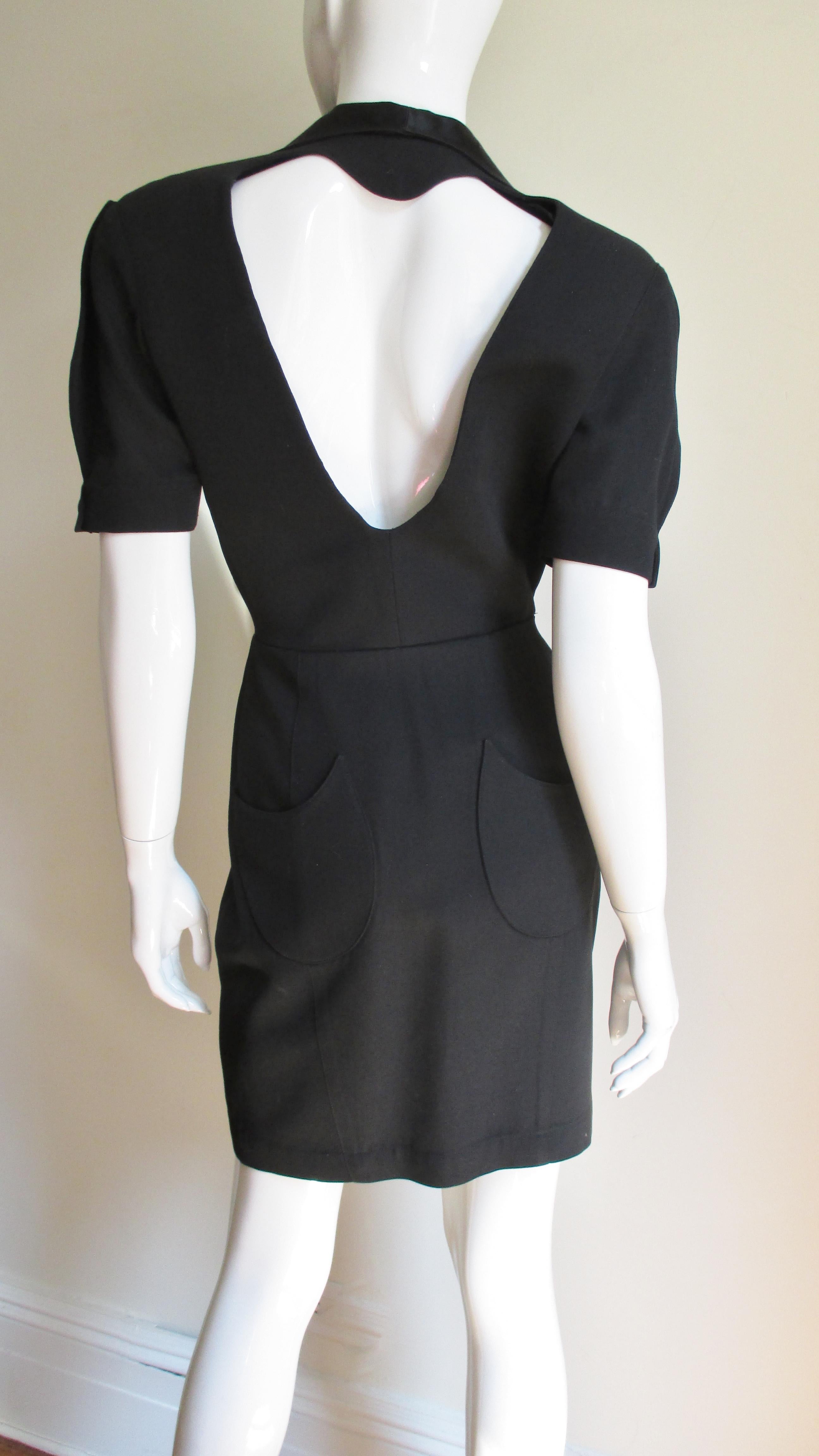 A fabulous dress in light weight black wool dress from Thierry Mugler.  It is gorgeous abstract shaped black silk lapels and short sleeves with snap cuffs.  It has a double breasted snap front closure with a straight skirt and 2 backside patch