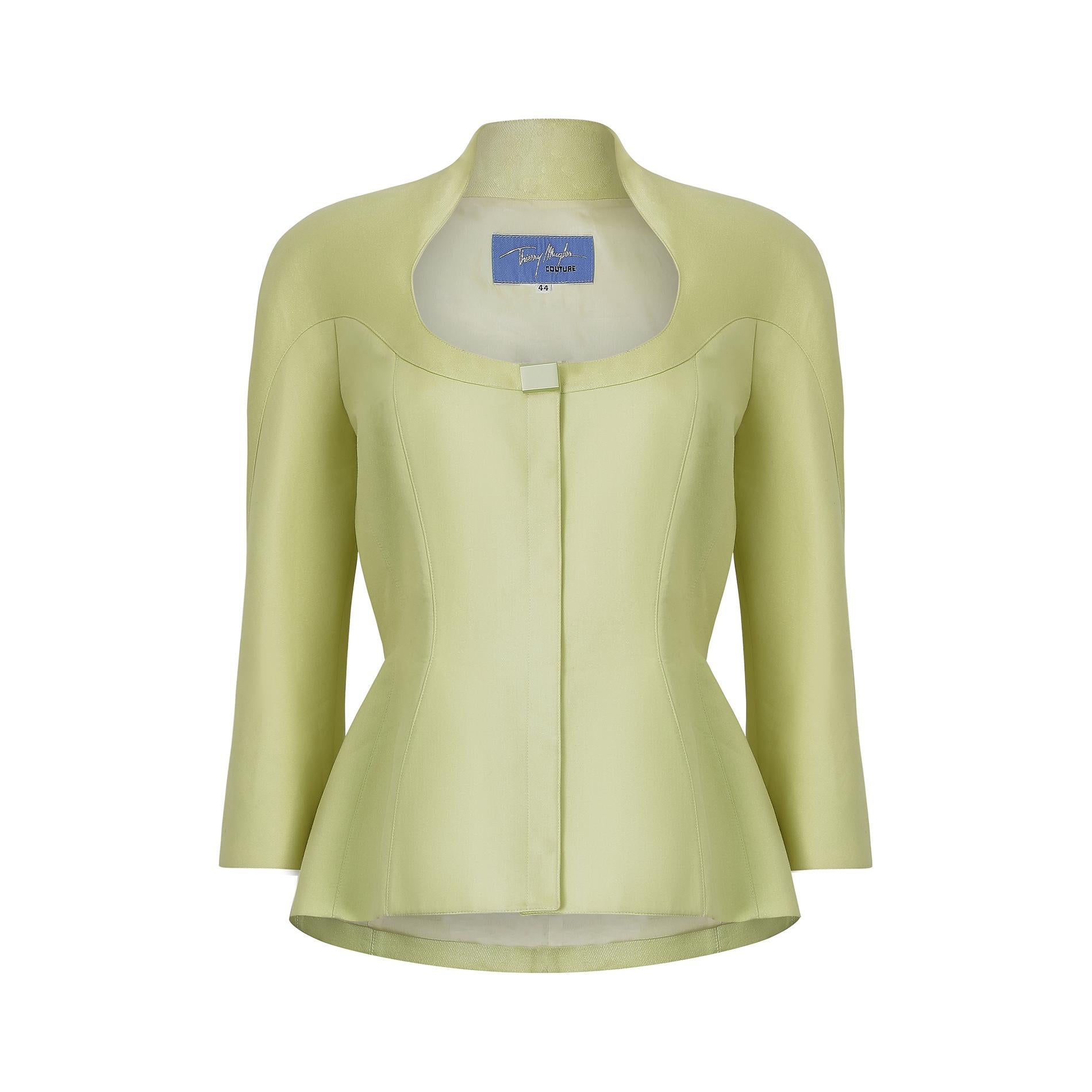 This 1990s Thierry Mugler couture jacket is cut from an unusual medium weight woven fabric.  It is a pale shade of chartreuse, almost lime green, with flecks of sparkle to create an iridescent effect.  Featuring a rounded front and high collar to