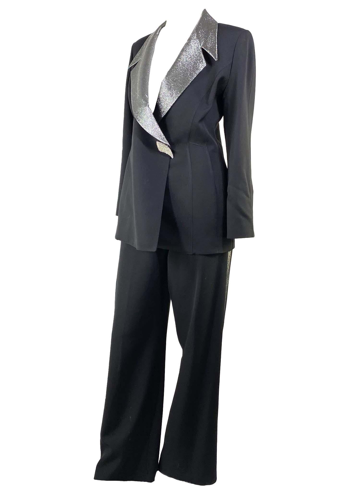 TheRealList presents: a silver lame Thierry Mugler pantsuit, designed by Manfred Mugler. From the 1990s, this suit features masterful design and tailoring. The blazer features a large sculptural silver lamé lapel and rhinestone encrusted snap
