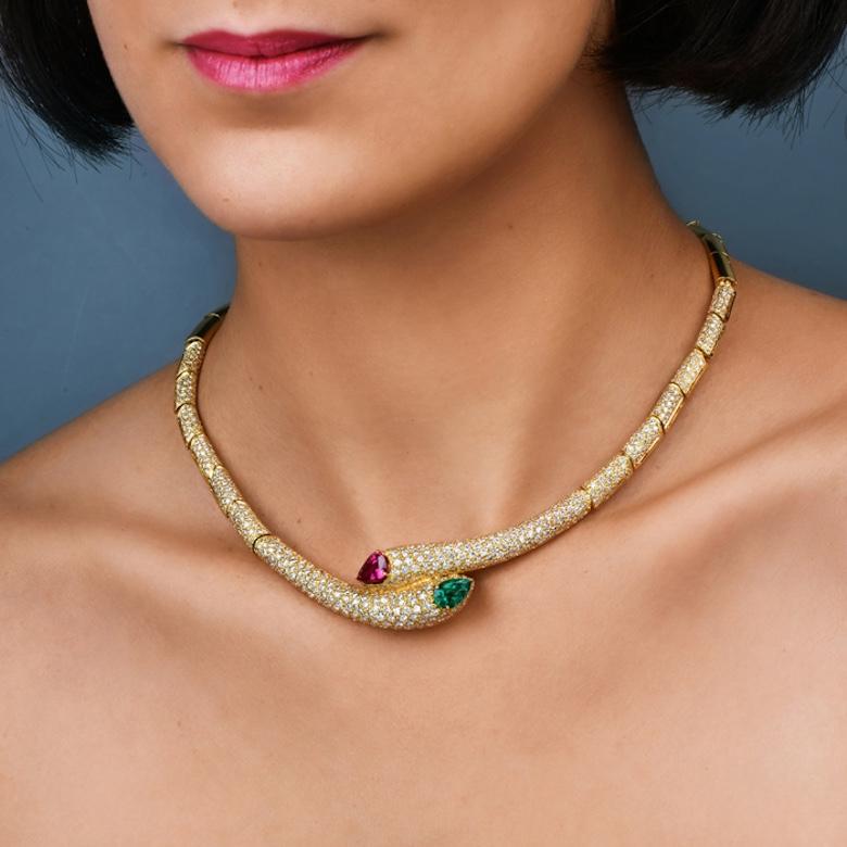 This Diamond, Ruby, and Emerald statement choker necklace is made in 18k yellow gold. Set with approx. 620 round diamonds; an approximate weight of 12.35  ct and H-I color and VS1-VS2 clarity. The genuine pear-shaped red Ruby weighs approx. 2.00