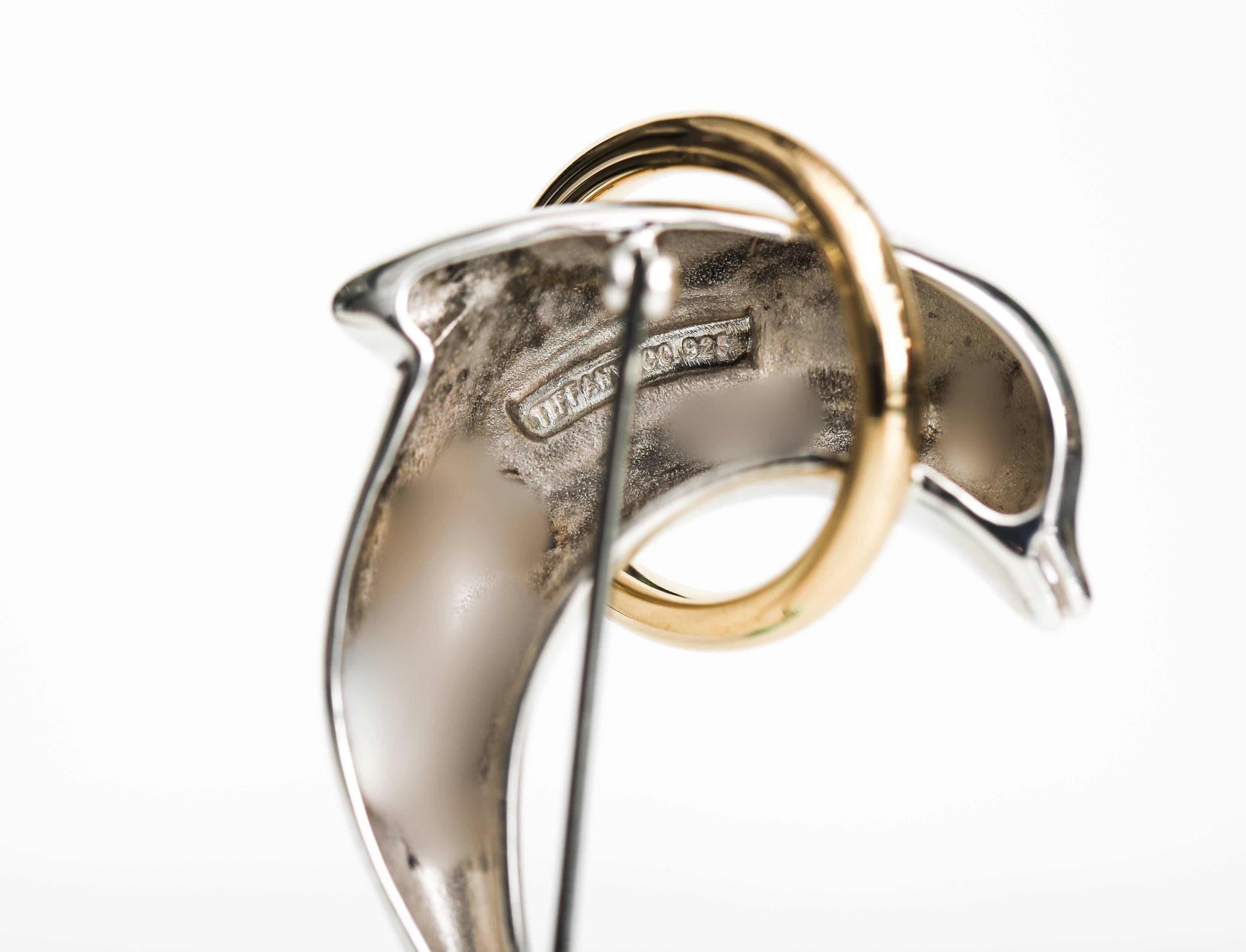 1990s Tiffany and Co. Dolphin Pin - 18 Karat Yellow Gold, Sterling Silver

Features a Sterling Silver Dolphin jumping through an 18 Karat Yellow Gold Ring. This sweet dolphin has delicate eye and mouth detail and 2 flippers. This Beautiful Brooch