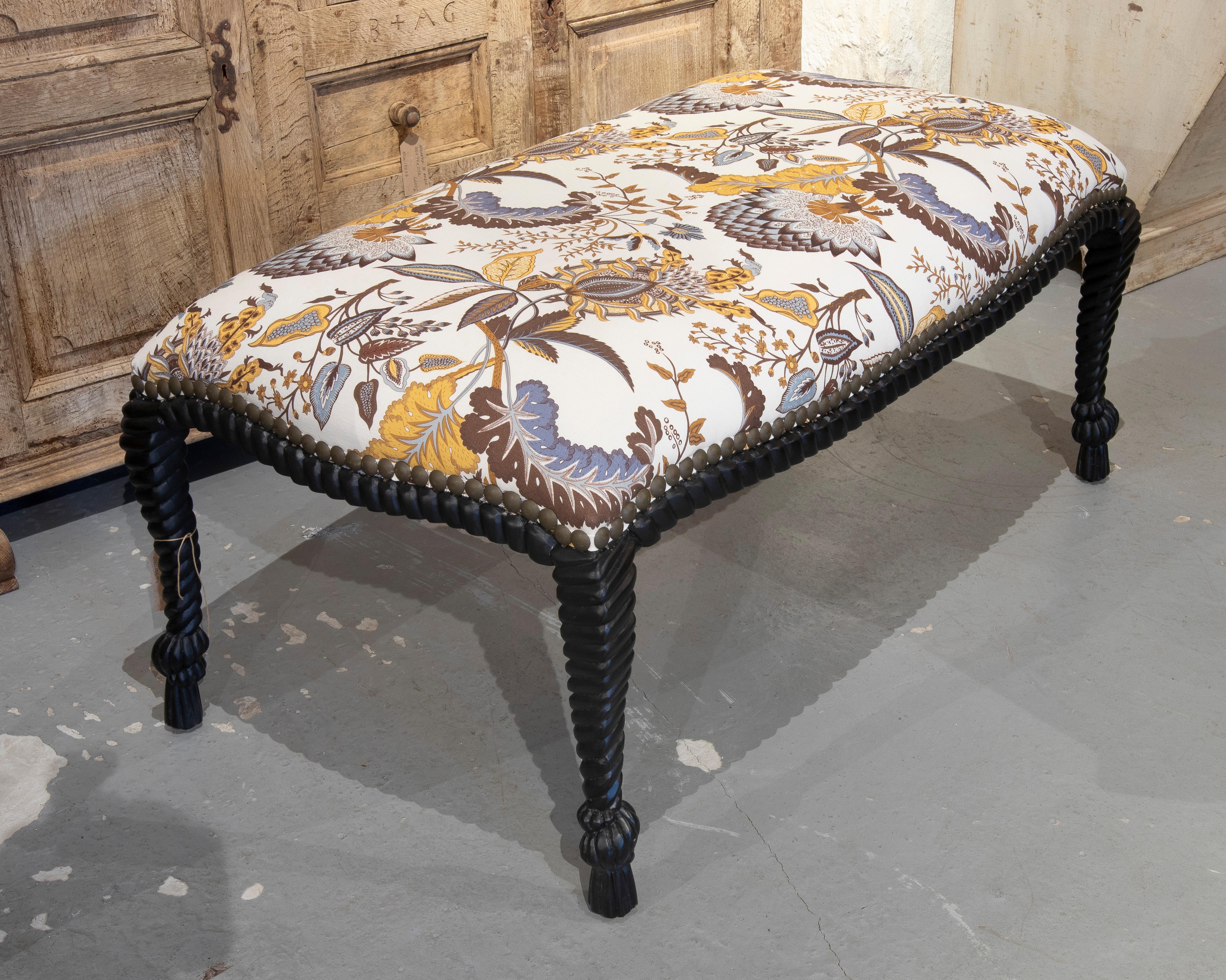 An elegant, classic-design bench with a carved wooden frame and spiral-turned legs, finished in a dark hue with decorative metal nailhead details. The seat is upholstered in a vibrant, vintage-inspired floral fabric in earth tones, ochre, and