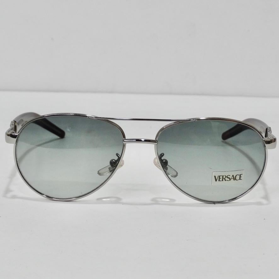 Ces lunettes de soleil de Versace, datant des années 1990, sont vraiment superbes ! Les lunettes de soleil parfaites de style aviateur sont dotées de verres bleus clairs et de détails bruns avec des accents argentés. Ce sont les lunettes de soleil