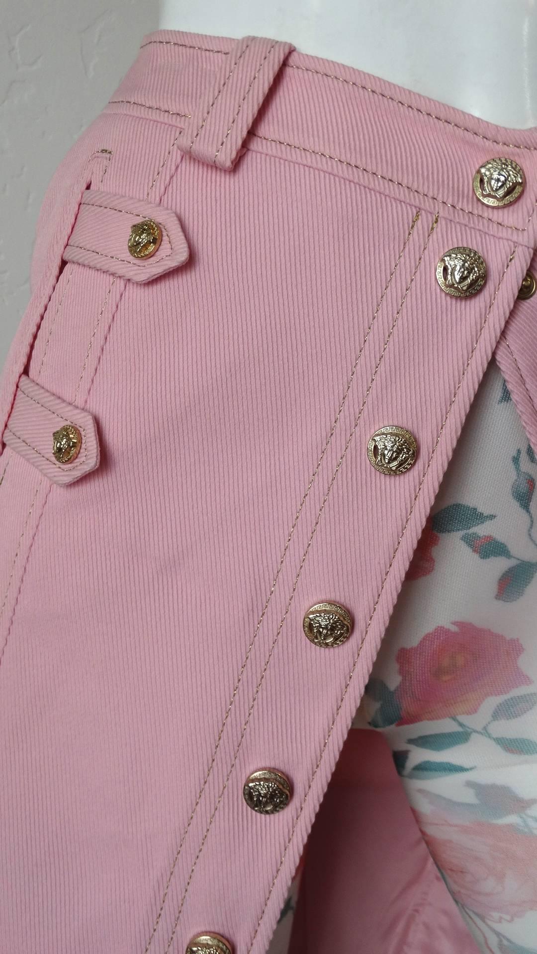 The most adorable 1990s Versace baby pink button up skirt! Made of a textured cotton fabric, made to look like denim- in a shade of soft pink. Accented with gold medusa head embossed buttons up the front of the skirt. Detailed denim inspired