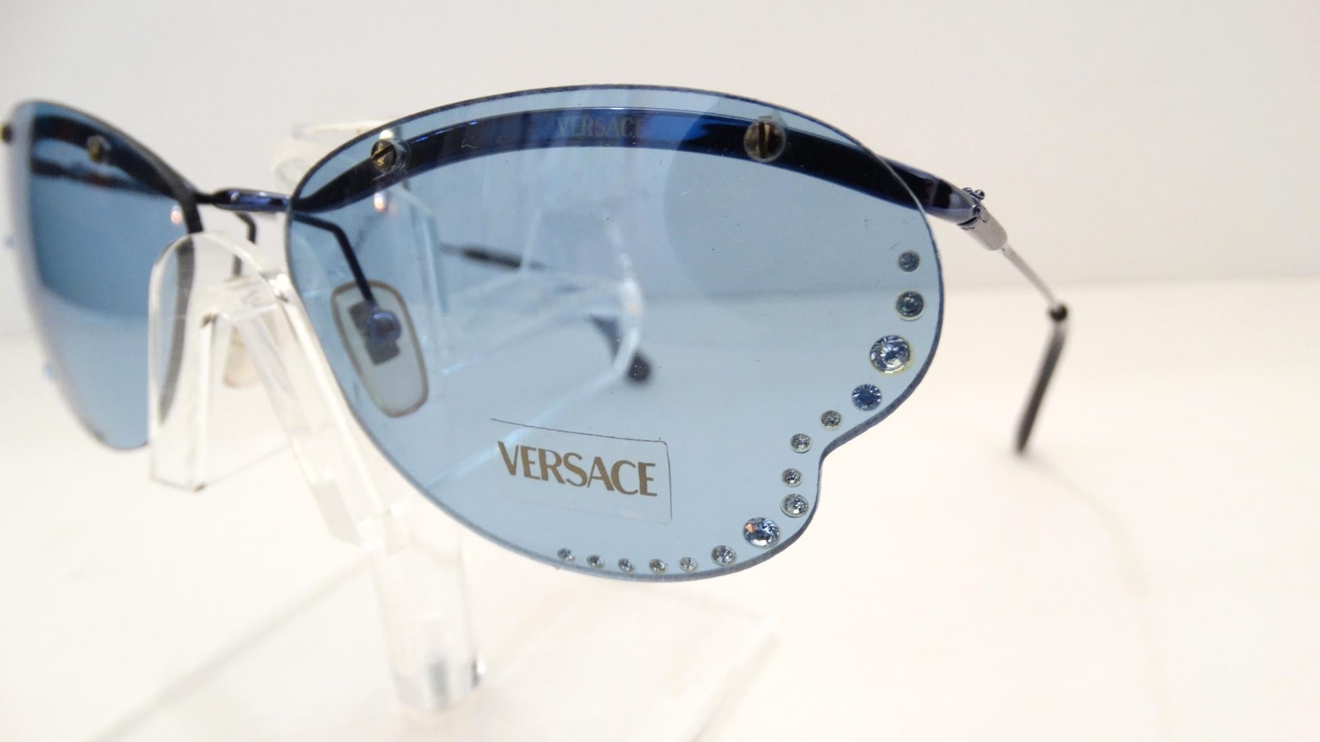 The Most Adorable Sunglasses Are Here! Circa 1990s, these dead stock Versace sunglasses feature rimless butterfly wing shaped lenses and tonal blue metal arms. Clear blue lenses are embellished with blue rhinestones. The perfect accent glasses that