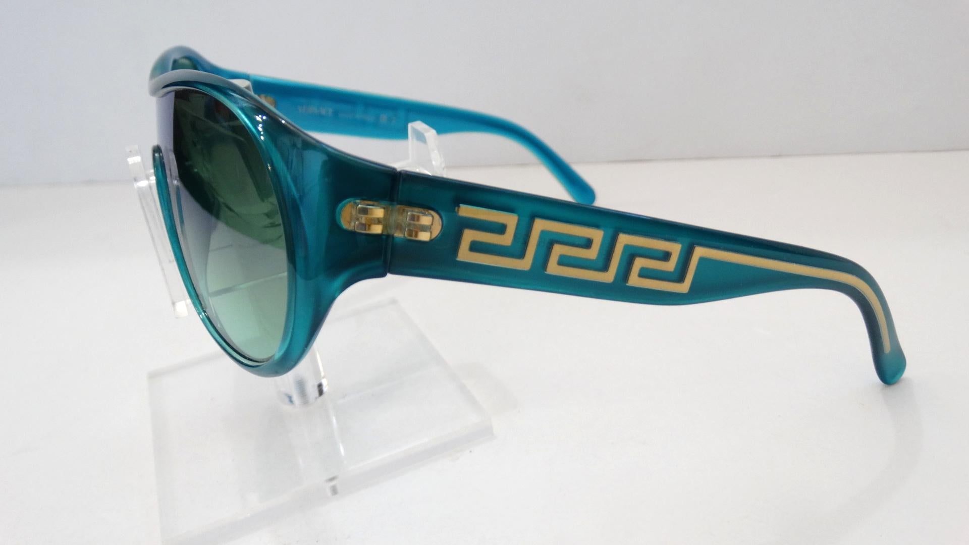 All Eyes On You While Wearing These Killer Versace Shield Sunglasses Circa 1990s! A dead stock treasure, these sunnies feature a vibrant and slightly shimmery turquoise frame with gold hardware and semi clear green/blue tinted reflective lenses. In