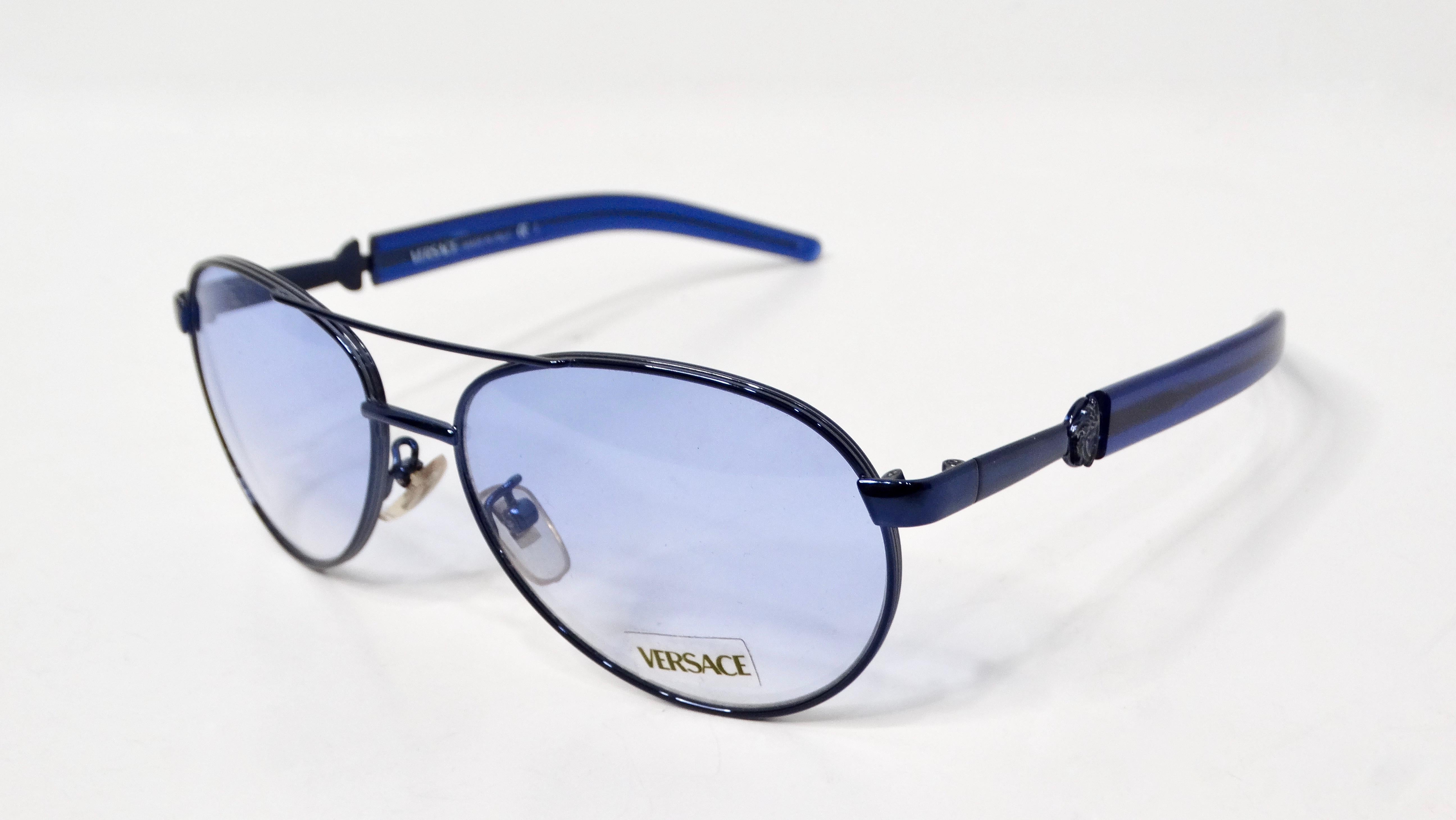 The 1990s Versace blue-tinted metal aviator sunglasses are a striking statement piece embodying the bold glamour of the era. The aviator frame, a timeless silhouette, is rendered in sleek metal with a distinctive blue tint, offering both style and