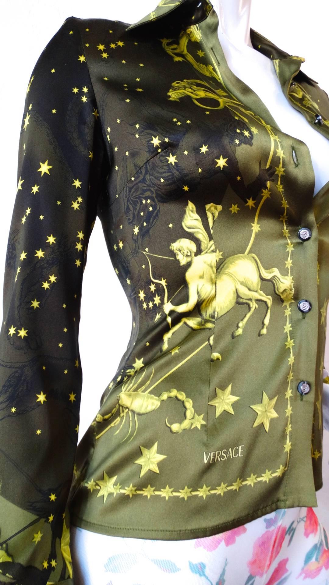 This amazing 1990s Versace constellation themed blouse will have you seeing stars! Incredible olive green ombre silk with golden constellation inspired print- featuring cherubs, stars, and the astrological sign motifs. Buttons up the front with