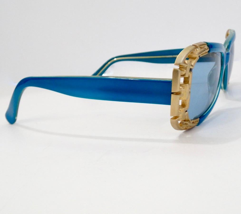 Never Go Unnoticed With These Electric Blue Versace Sunnies! Circa 1990s, these beautiful blue rounded rectangular sunglasses are a dead stock treasure and feature contrasting gold plated chain link metal accents as the outside trim. The perfect