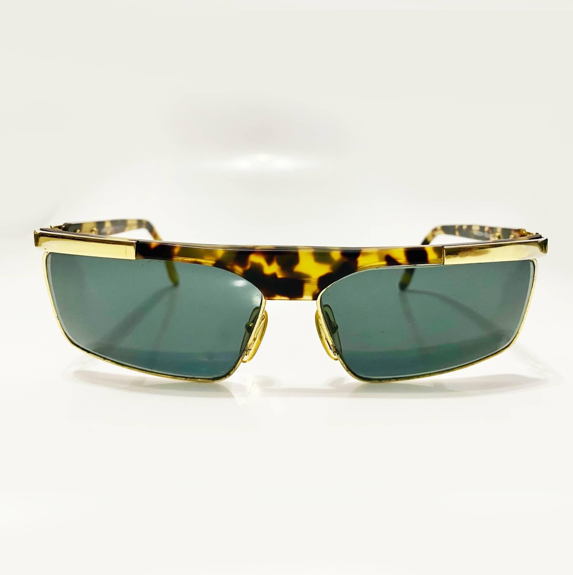 An iconic piece from the '90s, these Versace sunglasses feature a gold-tone metal frame with straight lines and brown lenses complemented by a tortoiseshell finish.

Condition: vintage, 1990s, very good, minimal wear 