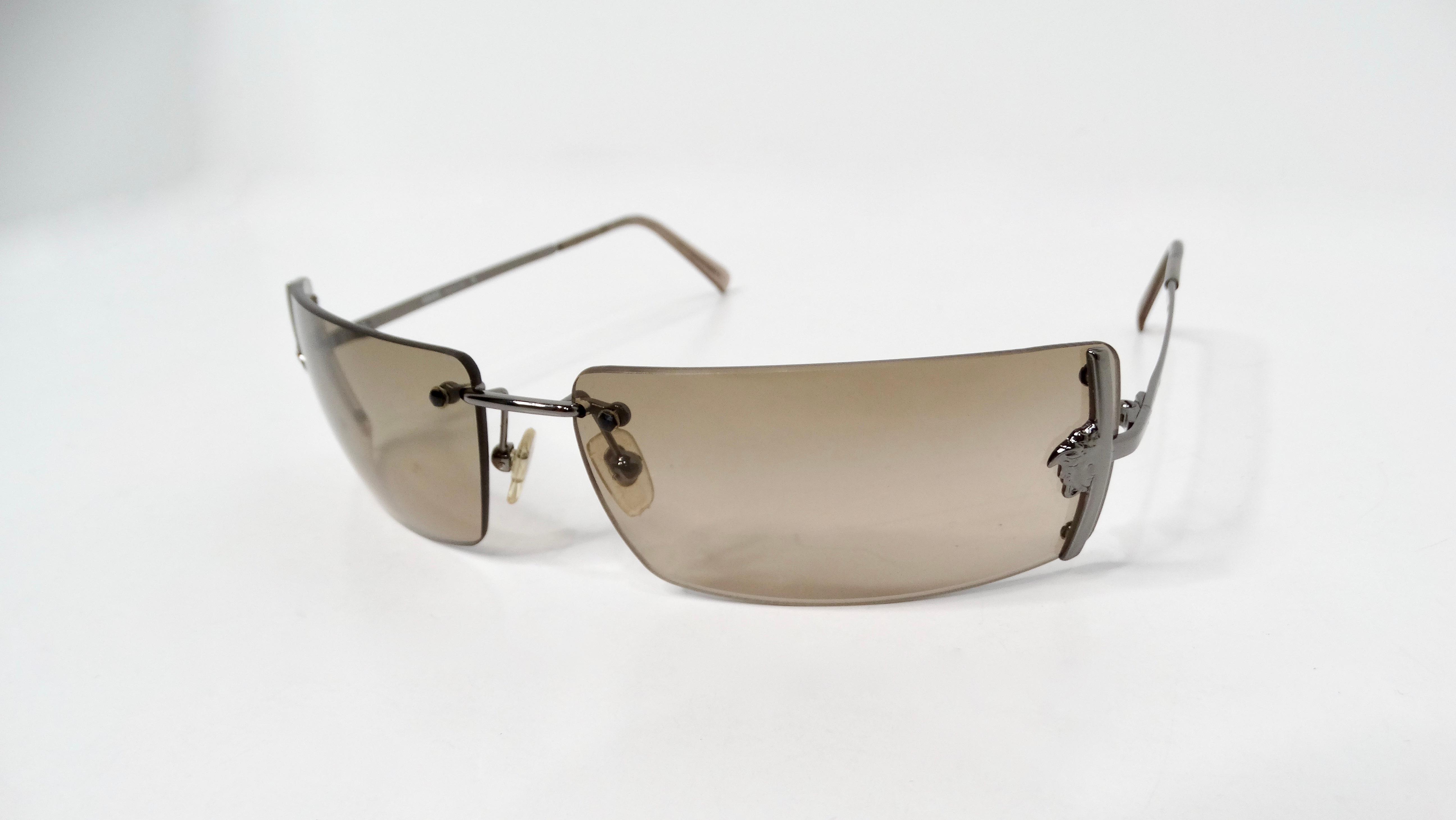 Fai un salto negli iconici anni '90 con questi splendidi occhiali da sole Versace Medusa Brown Tinted Rectangular Rimless Shield Metal, un accessorio essenziale che incarna lo spirito audace e avventuroso dell'epoca. Realizzati con lussuose aste in