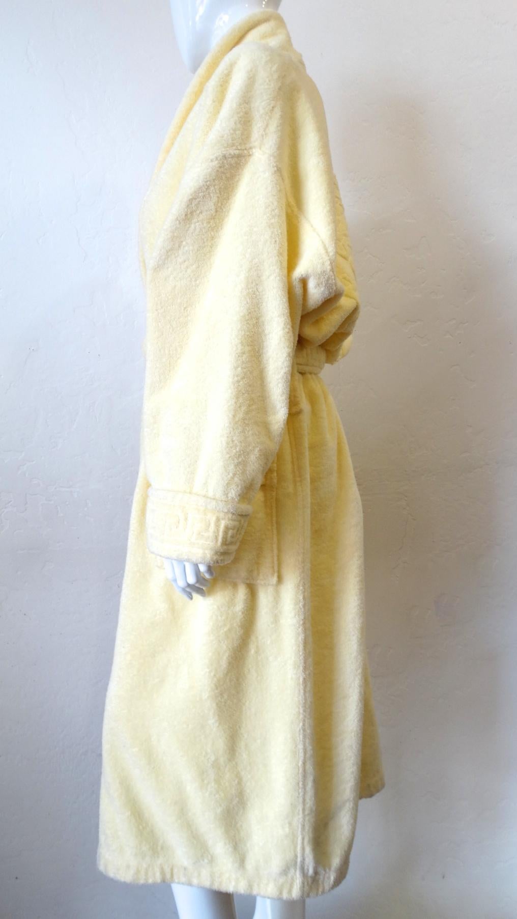 Relax In Style With This Versace Bathrobe! Circa 1990s, this pastel yellow billowy bathrobe features the iconic Medusa head on the back and the signature Greek keys along the trim of the sleeves, top of the two front pocket and the tie. The perfect